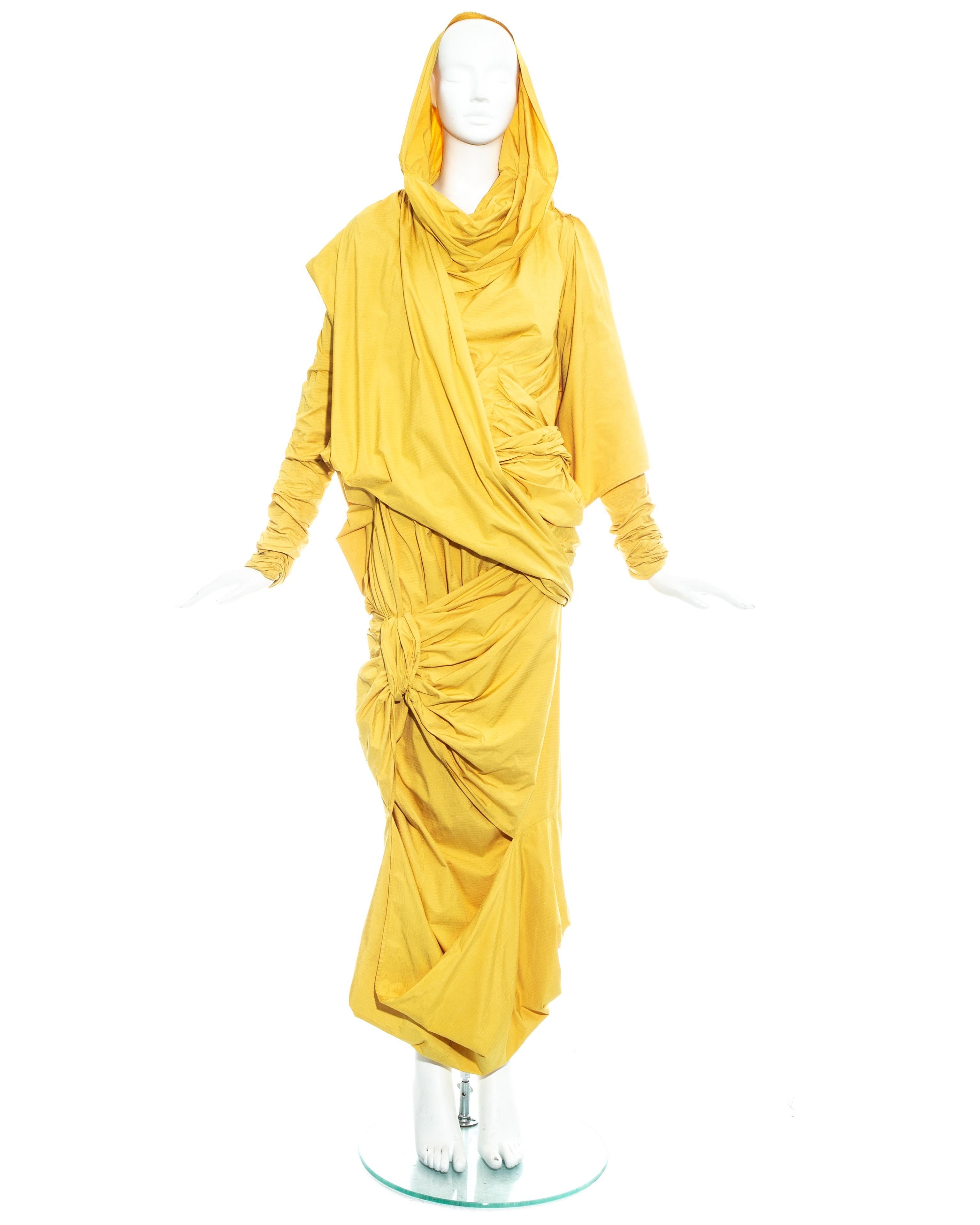 Issey Miyake, yellow parachute ensemble made from a high-density, crease-free woven fabric; thin and lightweight, with a texture like a piece of paper. Blouse with ruched double layered sleeves, pleated bust with asymmetric drape and optional hood.