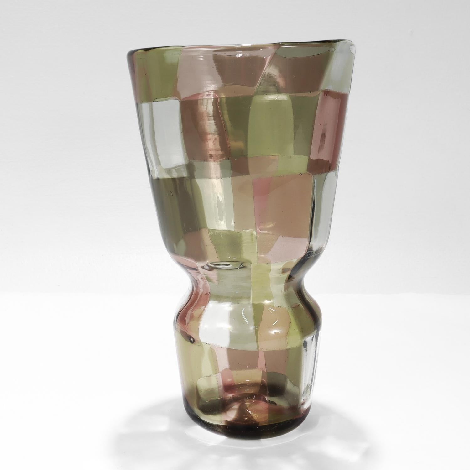 Un bel vaso in vetro artistico patchwork policromo di Pezzato. 

Di Venini.

Disegnato da Fulvio Bianconi (1915-1996).

Nella serie Pezzato Istanbul con tessere di colore giallo chiaro, chiaro, grigio talpa e viola.

Model No. 4402.

Con un segno di