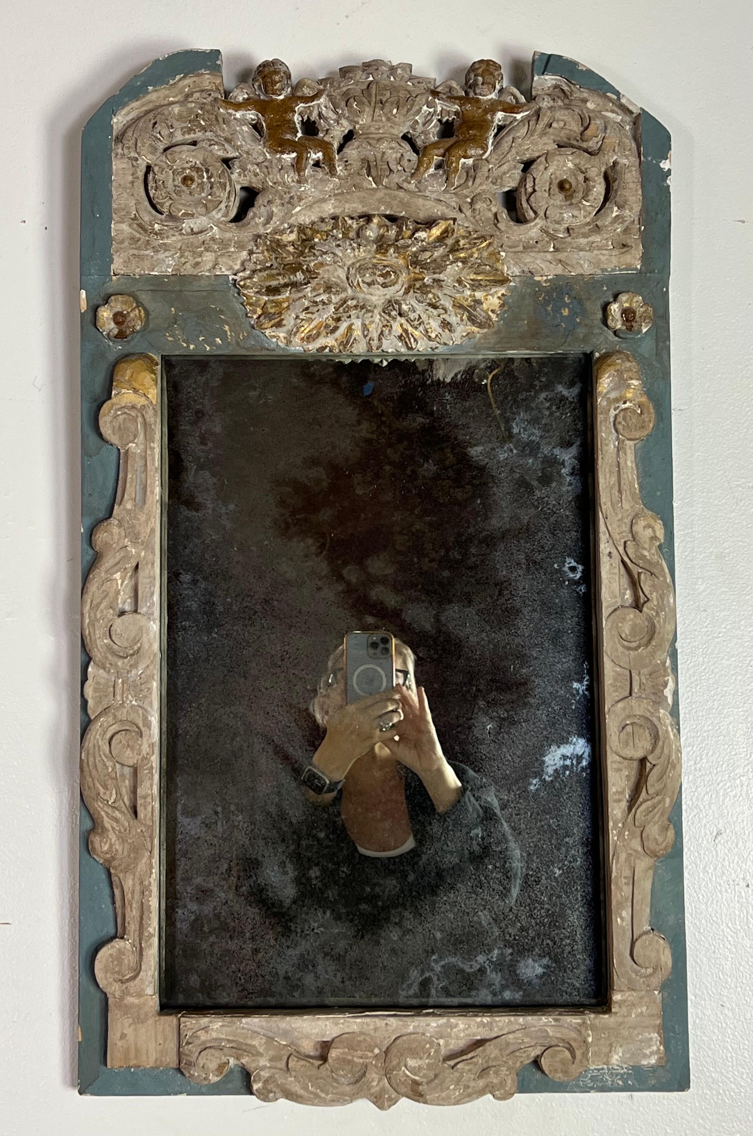 A charming small Italian mirror that speaks to the heart of Italian artistry and romantic design.  The mirror's frame is an exhibition of exquisite carvings, with scrolled acanthus leaves gracefully unfurling across its surface, embodying the