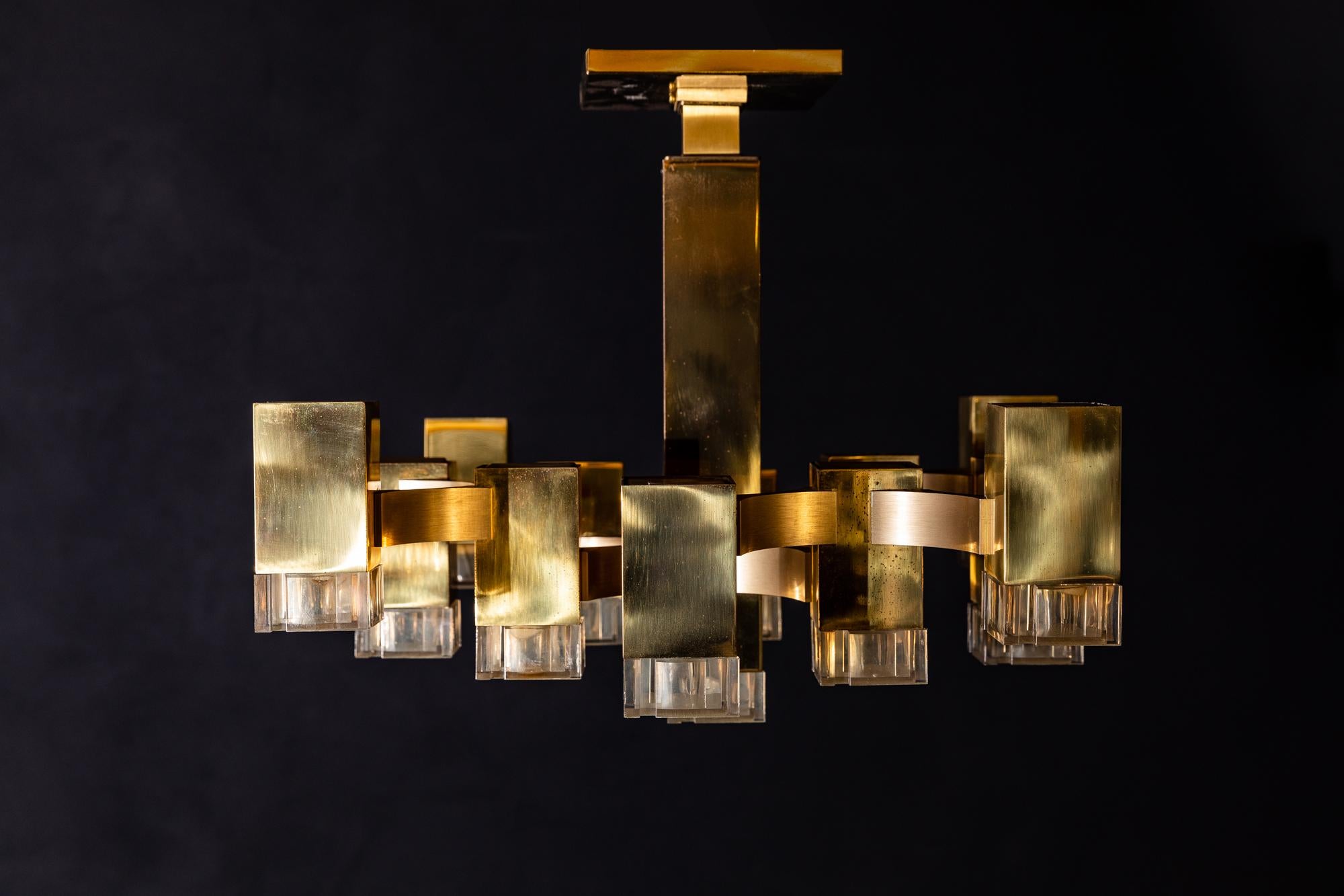Mid-Century Modern cubic chandelier designed by Gaetano Sciolari. This chandelier consists of 13 rectangular polished brass cubes with Lucite shades. The hanging chain can be adjusted to suit, and the original ceiling cap is included. Labelled on