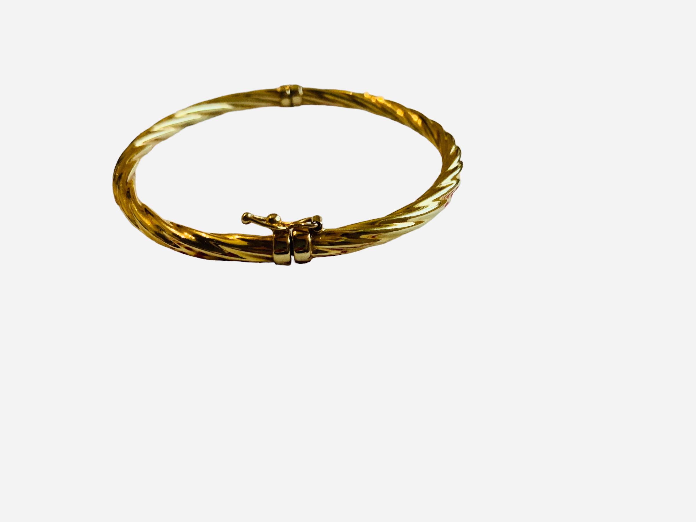 This is an Italian 14K yellow gold bangle. It depicts a rope, twisted curve or swirl like hinged hollow bangle. It has a round bracelet catch closure with a safety catch. It is hallmarked 14K Italy.