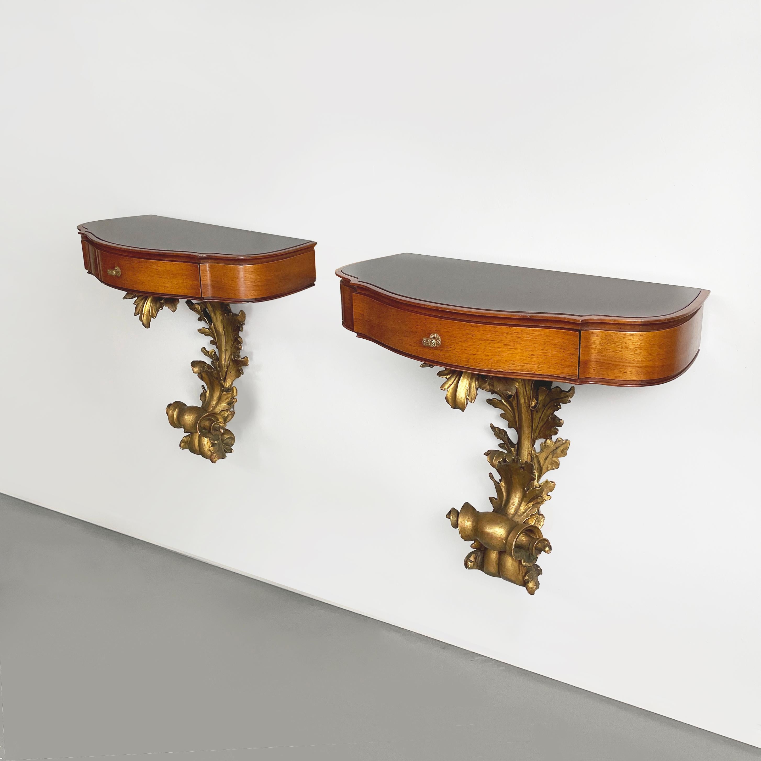 Italian 1600s style Bedside tables in golden finish wood, brass and glass, 1900s
Pair of wall-mounted bedside tables in wood and glass. The shaped top features back-painted brown glass and wooden profiles. On the front it features a drawer with a