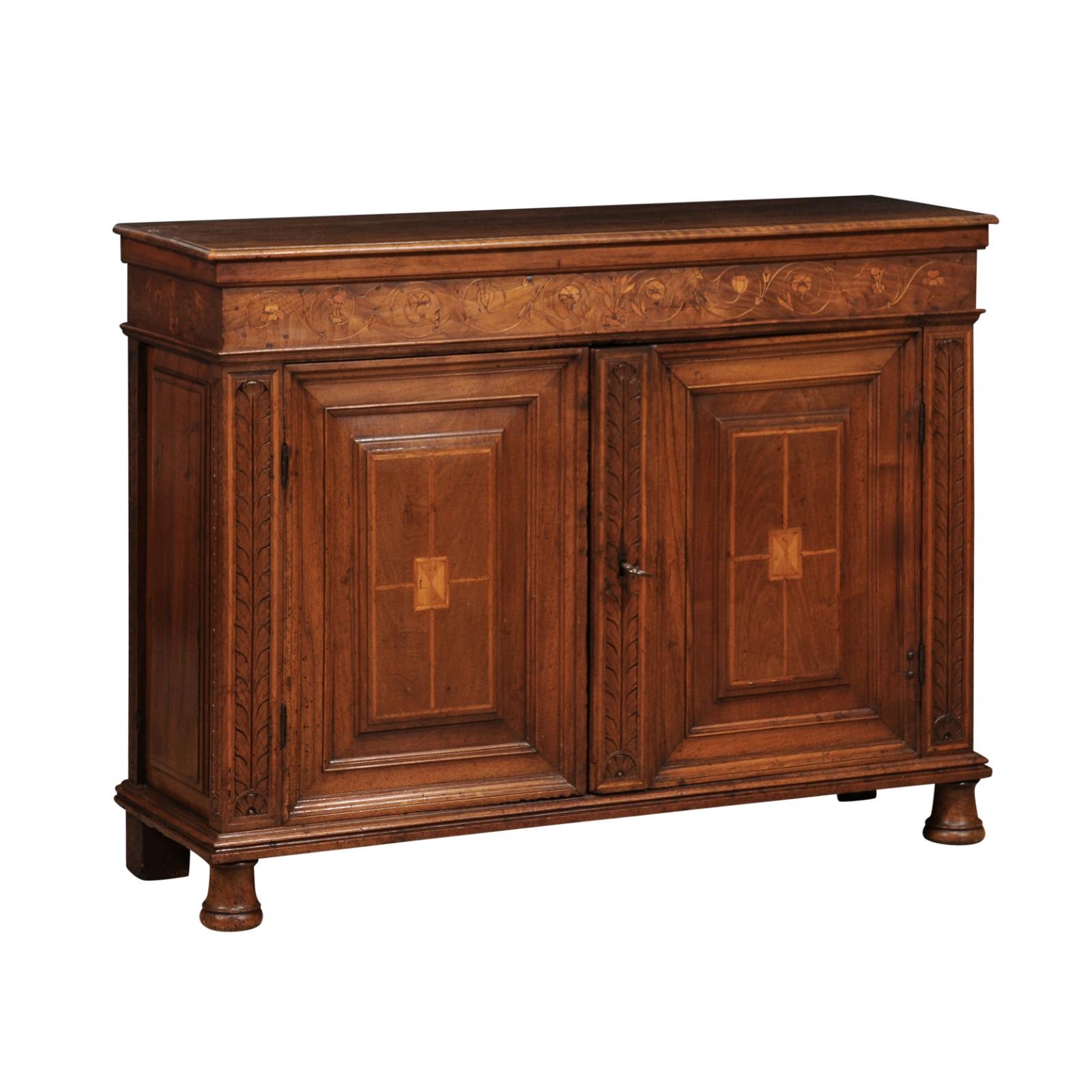 An Italian walnut buffet from circa 1620 with floral marquetry scrollwork made of lighter walnut and maple. This exquisite Italian walnut buffet, originating from circa 1620, is a true testament to the craftsmanship and artistic expression of the