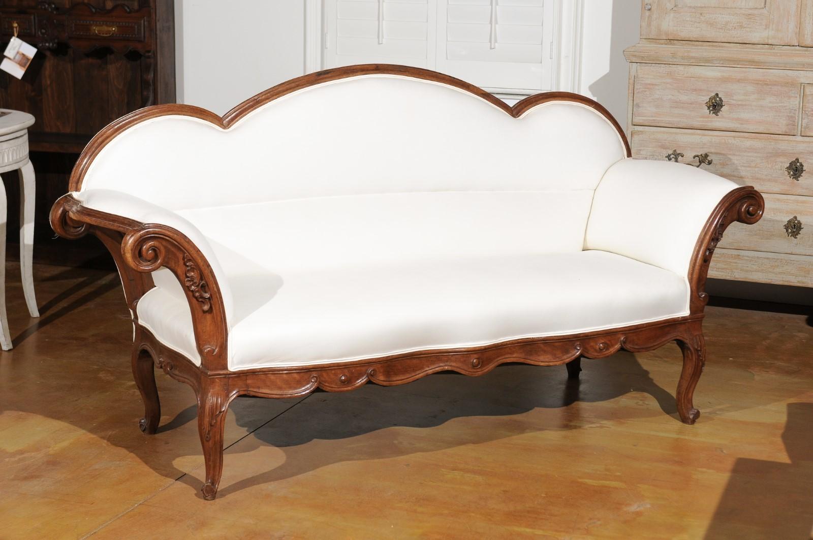 An Italian walnut sofa from the mid-18th century, with triple arched back, out-scrolling arms and upholstery. Born in Lombardy during the 1750s, this exquisite walnut sofa features a triple arched back connected to two out-scrolling arms, adorned