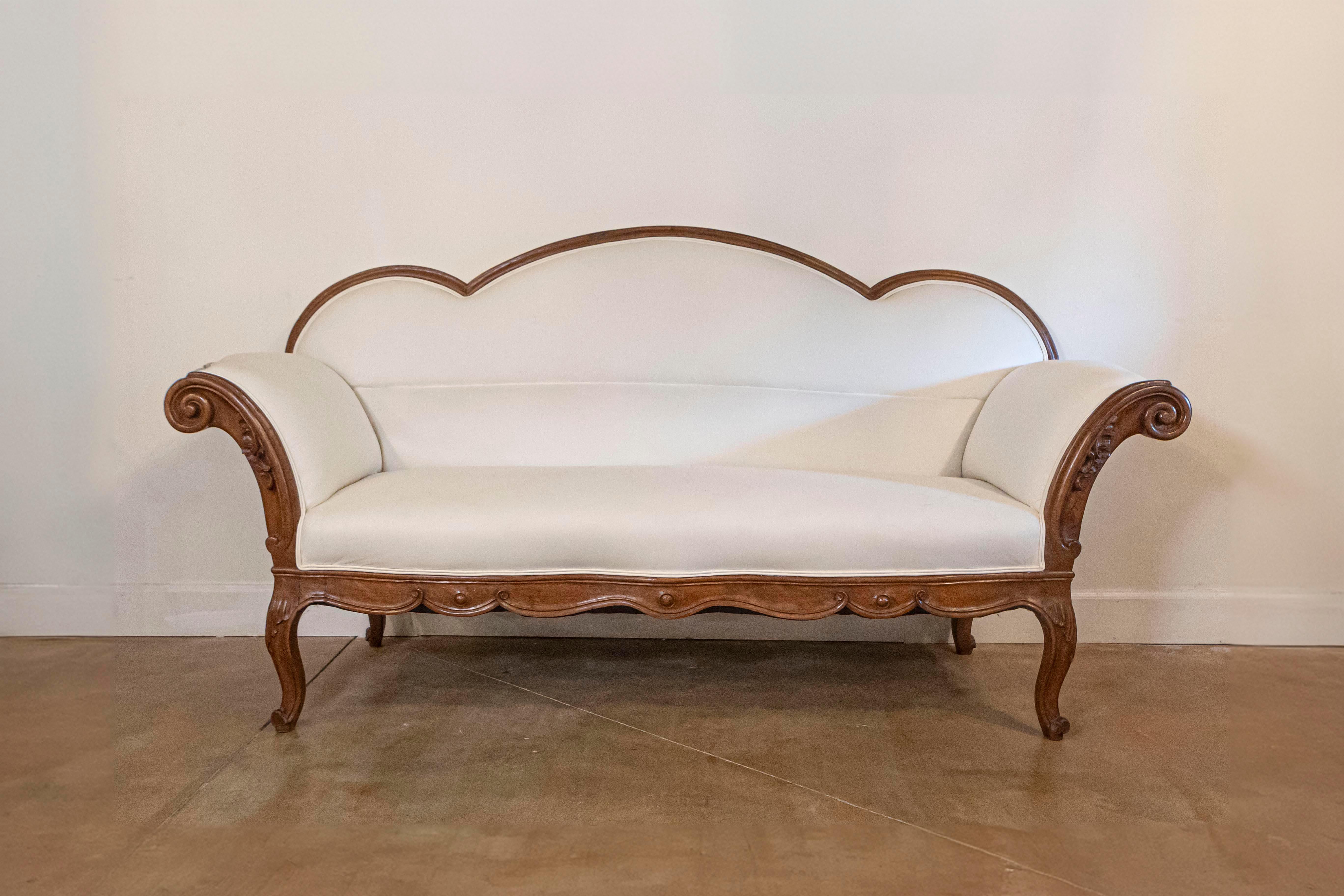 An Italian walnut sofa from the mid-18th century, with triple arched back, out-scrolling arms and upholstery. Born in Lombardy during the 1750s, this exquisite walnut sofa features a triple arched back connected to two out-scrolling arms, adorned