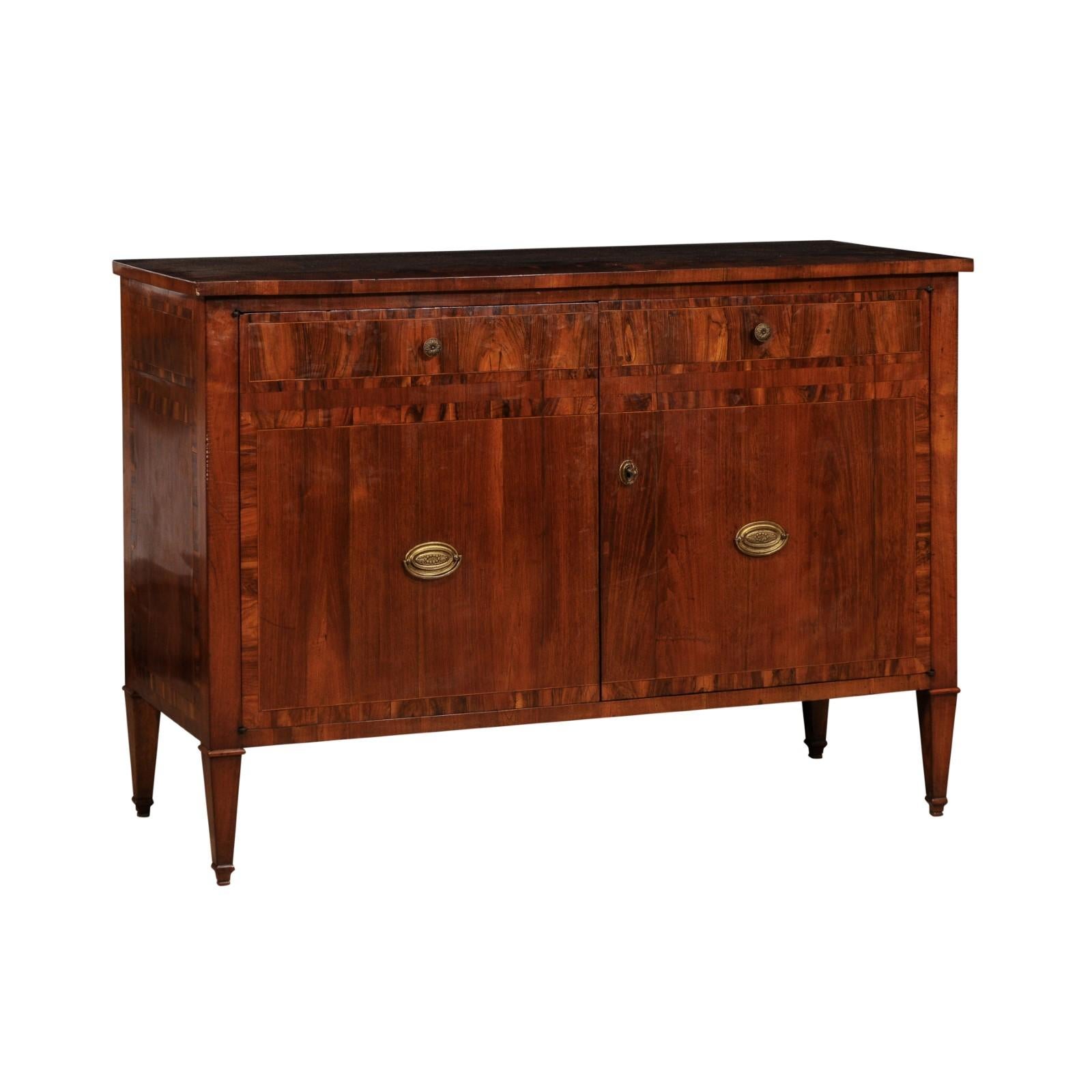An Italian walnut and mahogany buffet from circa 1780 with cross banding, two doors and tapered legs. Infuse your home with the timeless elegance of this Italian walnut and mahogany buffet, a magnificent piece dating back to circa 1780. Crafted with
