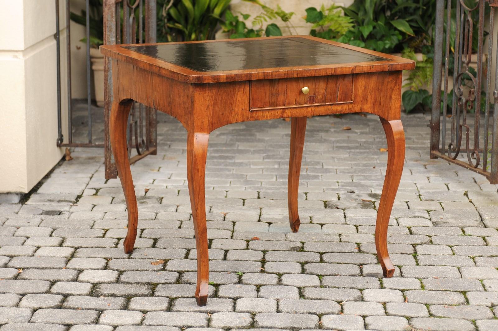 An Italian walnut veneered game table from the late 18th century with leather top inset, single drawer and cabriole legs. Born in the later years of the 18th century, this Italian game table features an exquisite walnut-veneered body, topped with an
