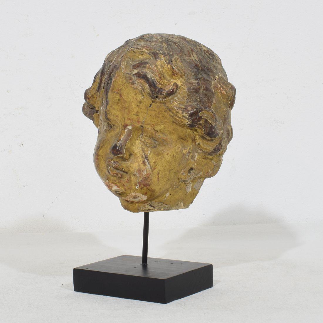 Beautiful giltwood angelhead.
Italy, circa 1650-1750
Weathered and small losses. 
Measurement here below inclusive the wooden base.
H:18,5cm  W:11cm D:11,5cm 