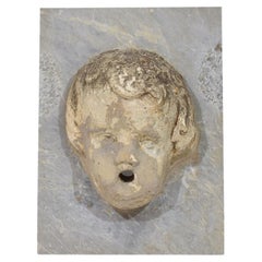 Testa di fontana di cherubino in pietra intagliata del XVII-XVIII secolo su pannello di marmo