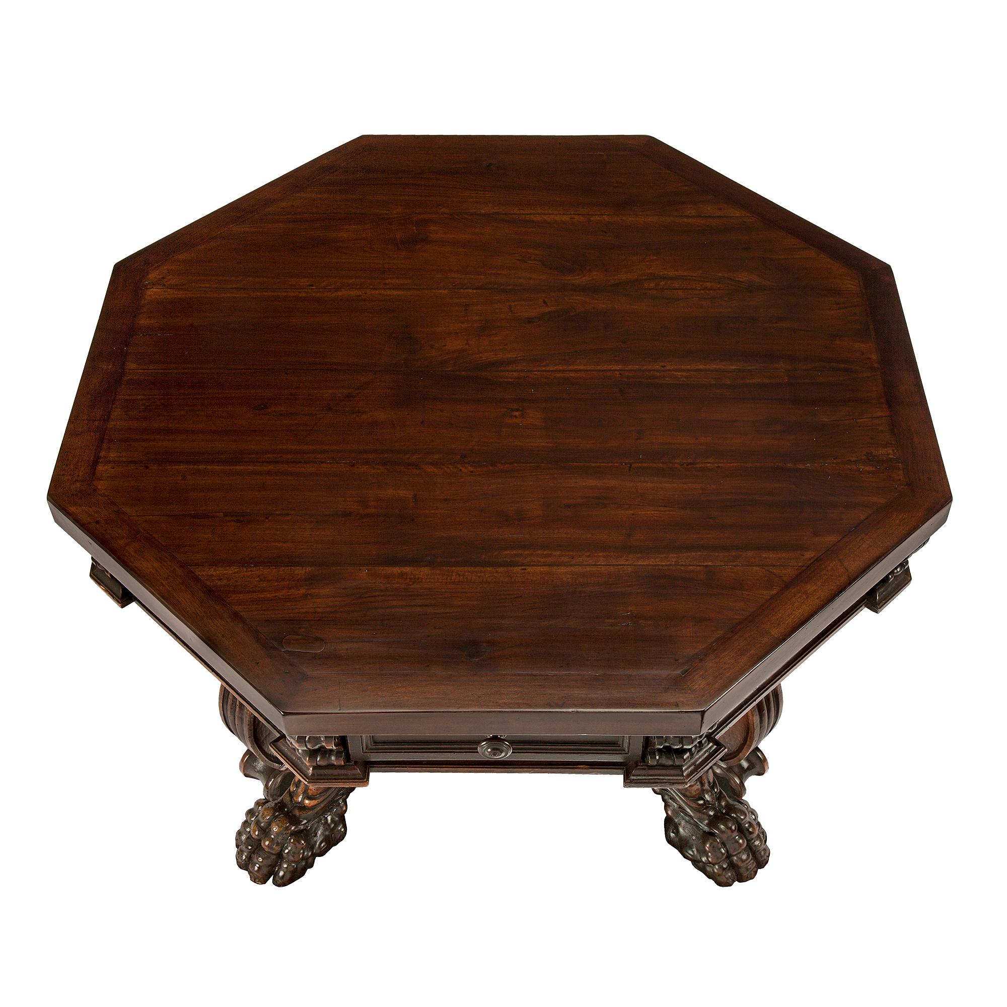 A handsome Italian 17th century Baroque period solid walnut octagonal center table. The table is raised by four wonderfully scrolled legs with richly carved paw feet and outstanding foliate designs, centered by a large inverted bottom finial. At the