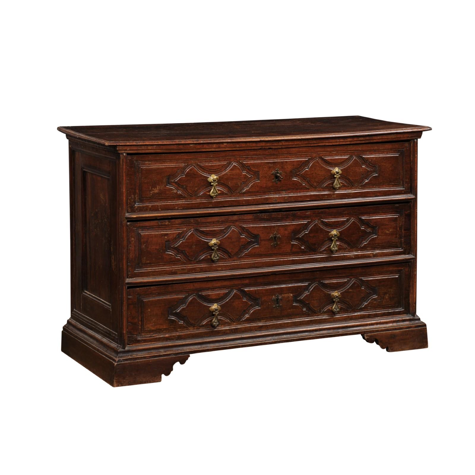 An Italian Baroque period walnut commode from the 17th century with three drawers, carved panels, bracket feet, bronze hardware and great rustic character. Created in Italy during the 17th century, this walnut commode features a rectangular top with