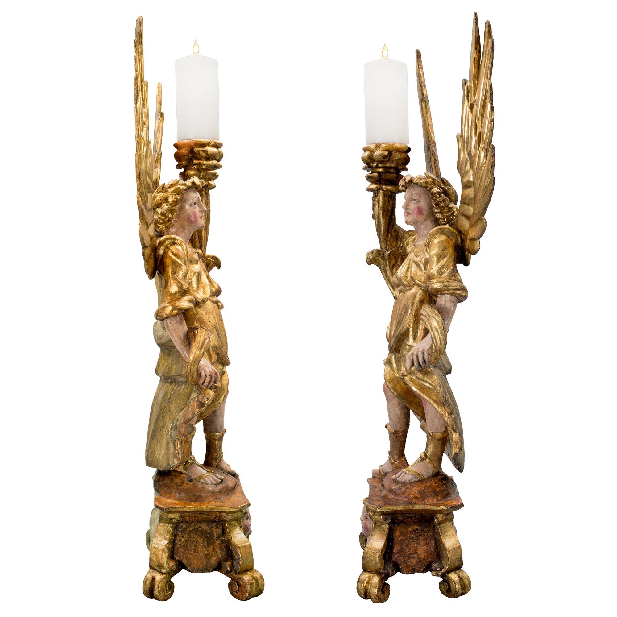 A pair of exuberant Italian 17th century candleholders from northern Italy, circa 1670. Each polychrome and giltwood candle holder is raised on scrolled feet below a uniquely shaped pedestal with winged cherub masks. Above are wonderful winged