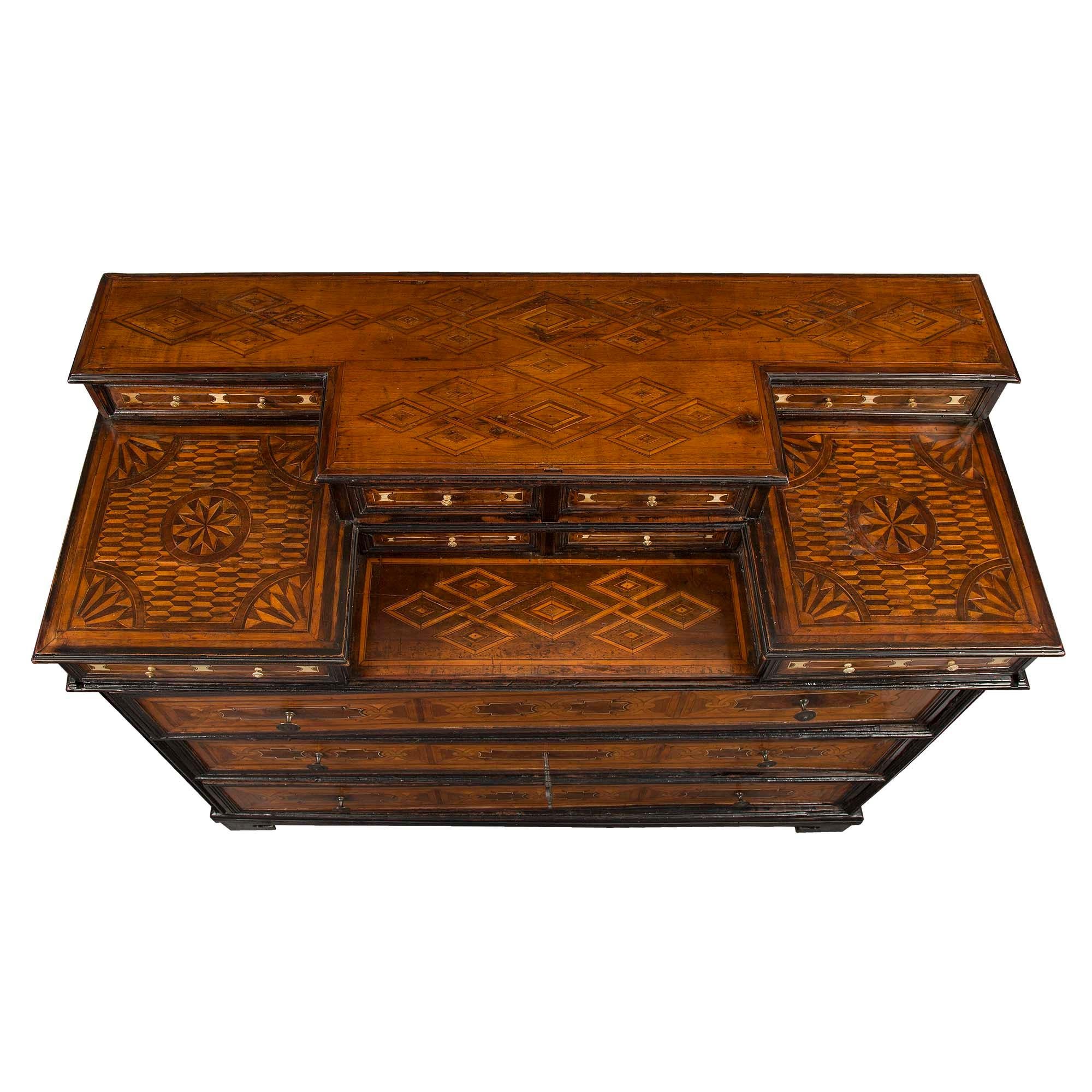 A handsome and very unique Northern Italian 17th century ebonized fruitwood and walnut inlaid chest, circa 1680. The chest is raised by a mottled support below three impressive drawers with turned pulls and striking interlocking bone inlays. Each