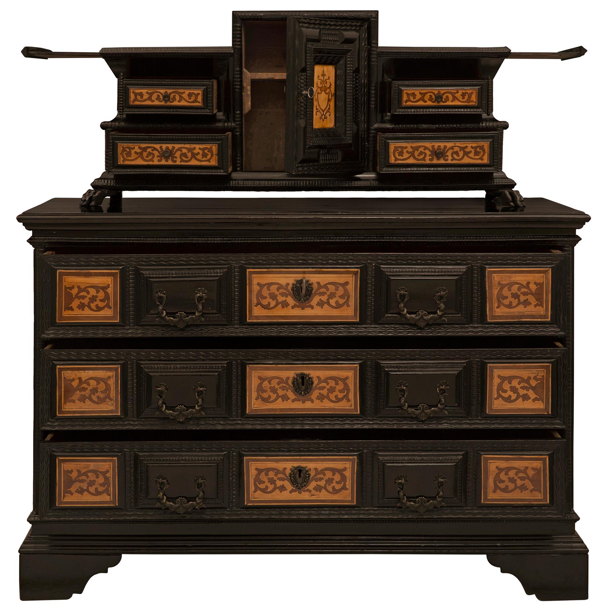An extremely handsome Italian 17th century ebonized fruitwood, walnut, and tulipwood Baroque chest with its original hutch. The chest is raised by scalloped support below three impressive drawers. Each drawer displays exceptional carvings and