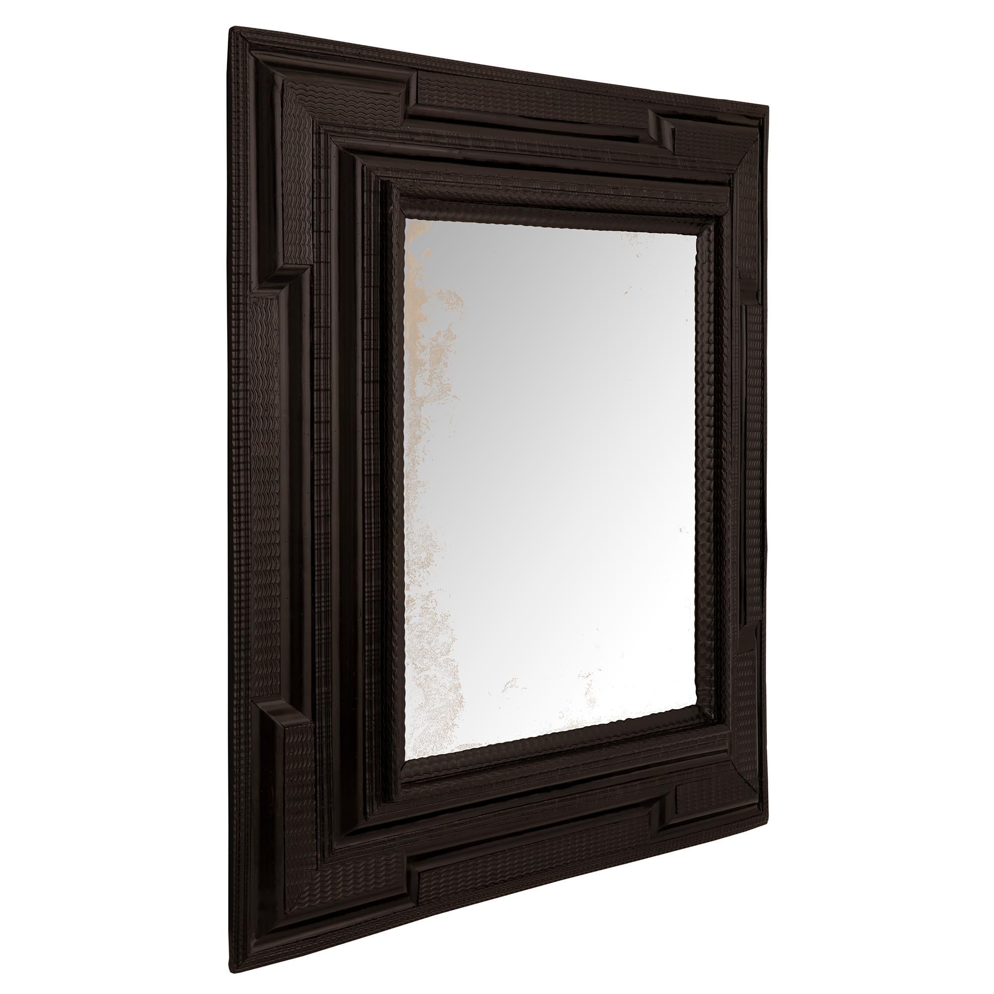 A beautiful and most impressive Italian 17th century ebony Florentine mirror. The original mirror plate is framed within a handsome thick ebony border. The border displays unique finely carved waved designs spread over the most decorative mottled