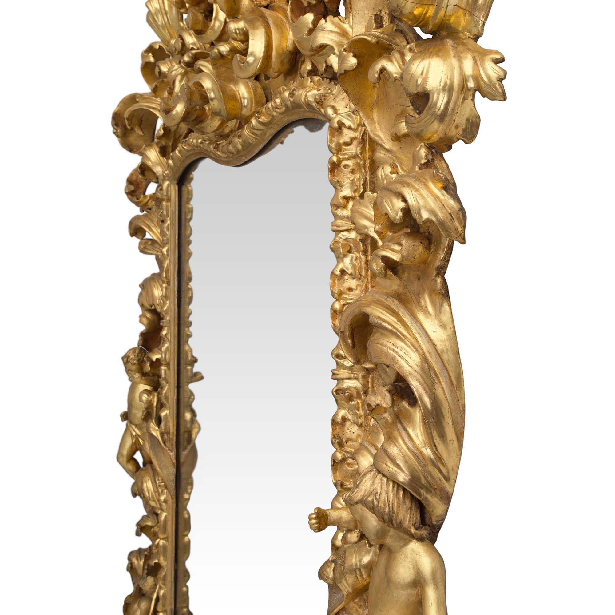 Un spectaculaire et très impressionnant miroir en bois doré baroque italien du 17ème siècle de style Louis XIV. Le miroir est surélevé par deux supports fantaisistes à volutes en 