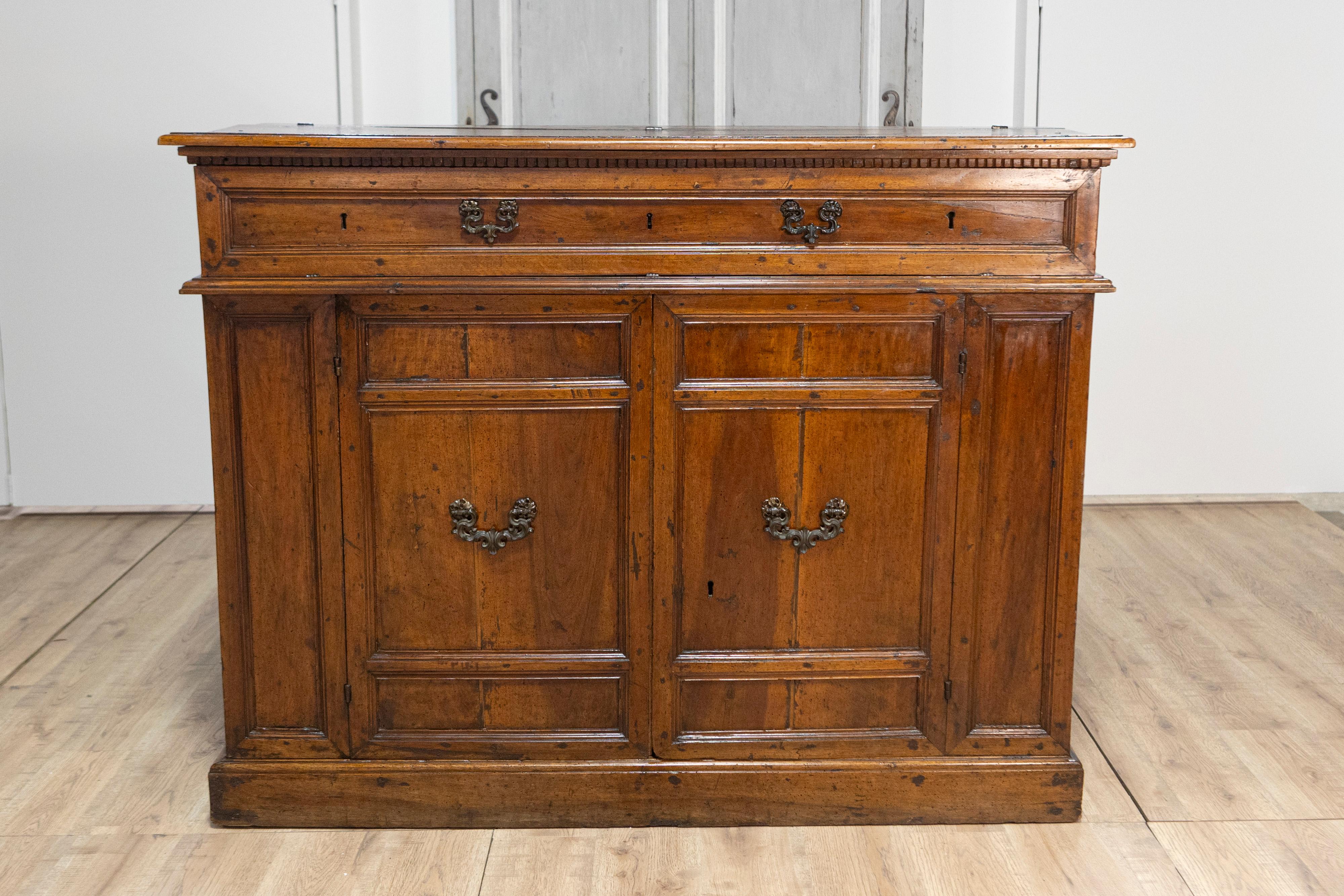 Ein italienisches Nussbaumbuffet aus dem 17. Jahrhundert mit Hängefront, versteckten Schubladen, zwei Türen und geschnitzter Zinnenleiste. Dieses außergewöhnliche italienische Nussbaumbuffet aus dem 17. Jahrhundert besticht durch seinen historischen