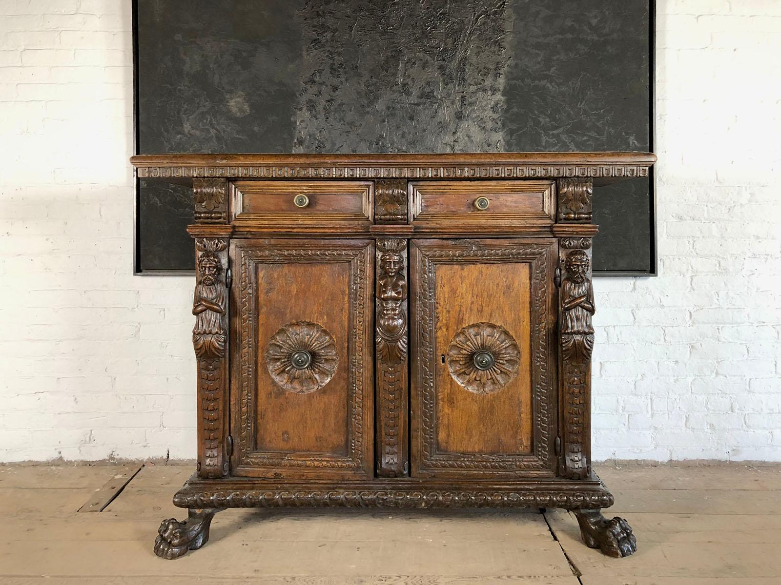 Mid-size Italian credenza with a deep warm patina, the molded top with a dentil-decorated edge above two drawers with brass knobs, separated by decorative acanthus scrolls, two doors, decorated with carved moldings and center rosettes featuring