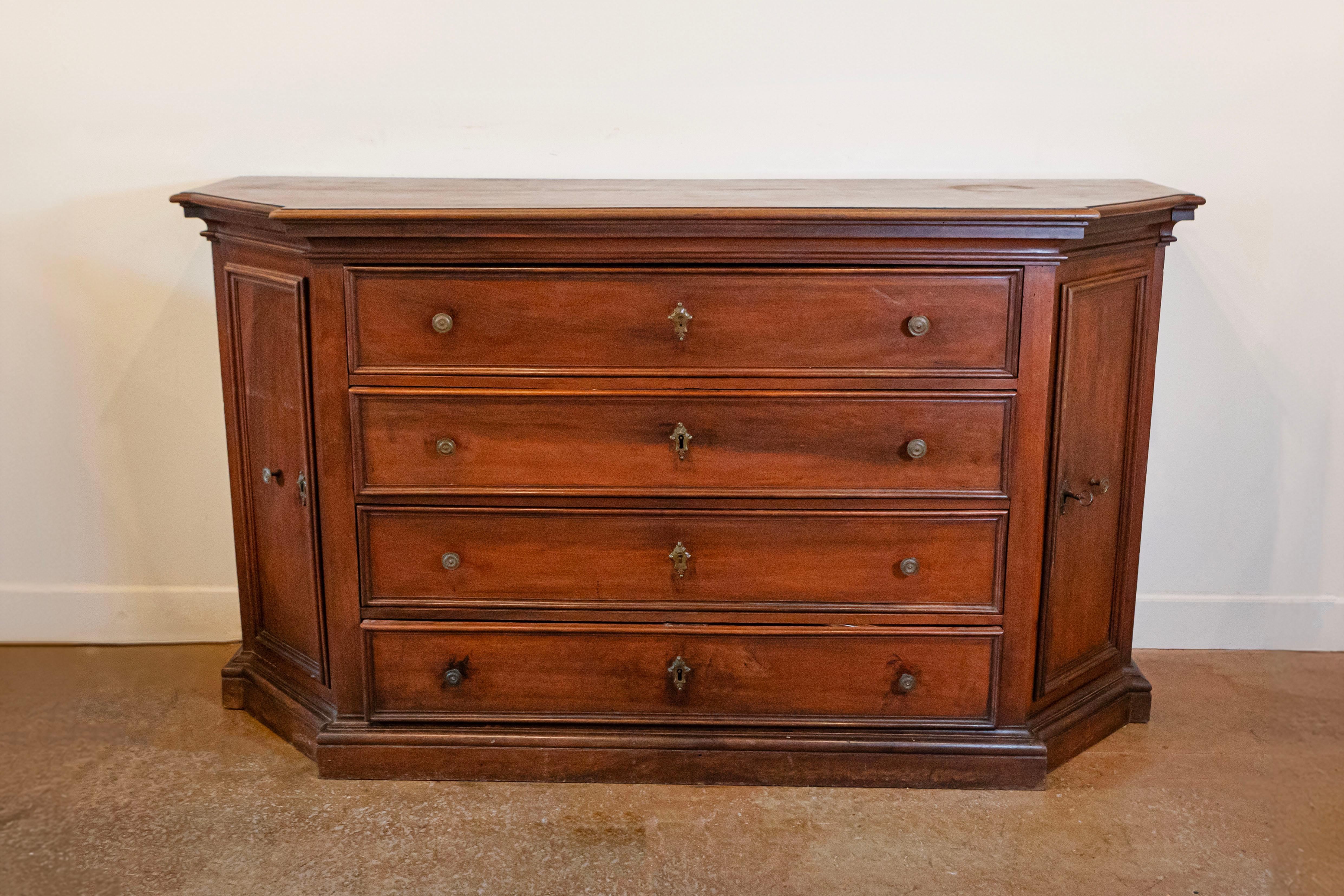 Un comò in noce italiano del XVII secolo con quattro cassetti, lati inclinati con ante, accenti modanati e carattere rustico. Creato in Italia durante il XVII secolo, questo comò in noce presenta un piano rettangolare con lati inclinati e frontale
