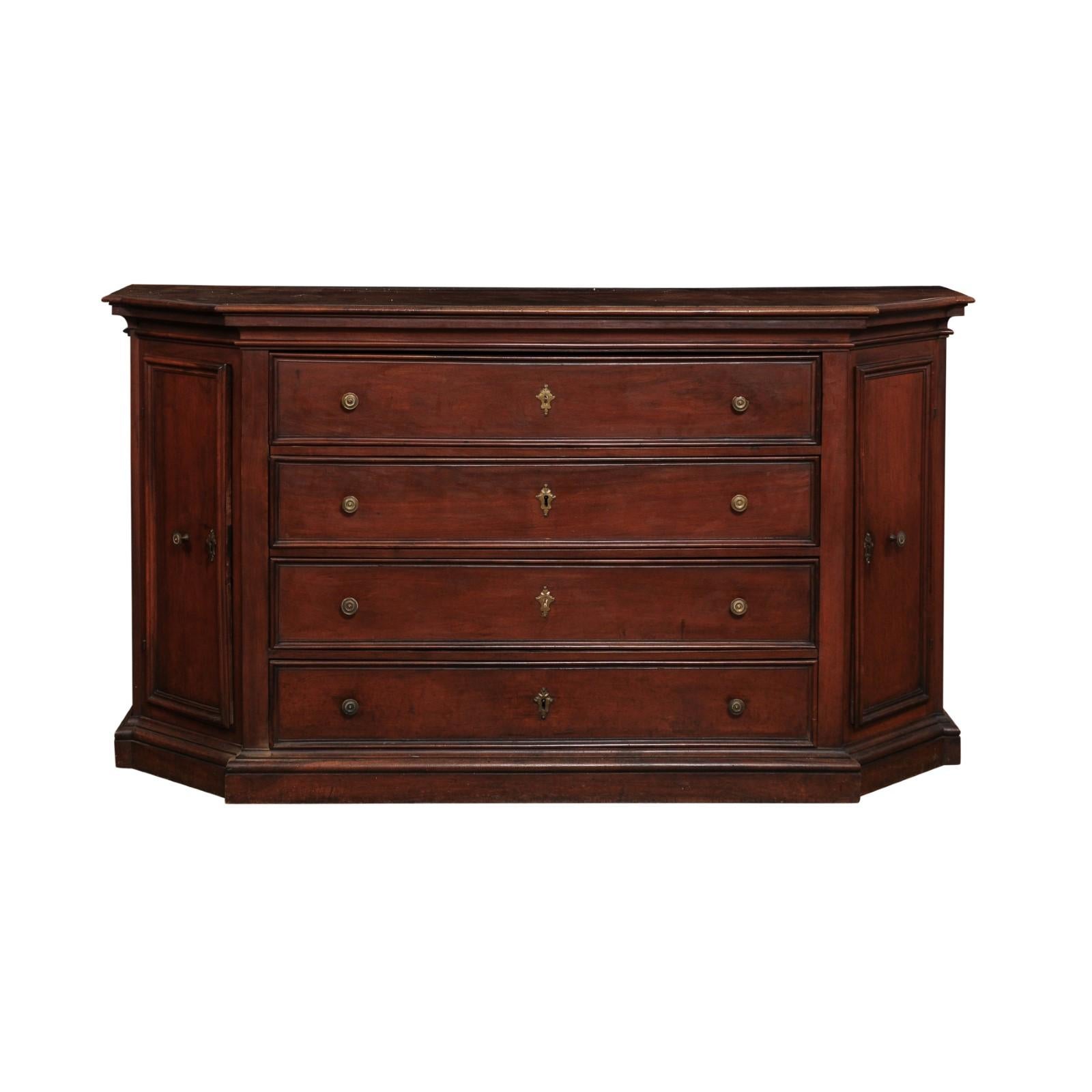 An Italian walnut dresser from the 17th century with four drawers, protruding front, canted sides with doors, bronze hardware, molded accents and rustic character. This exquisite Italian walnut dresser from the 17th century is a true embodiment of