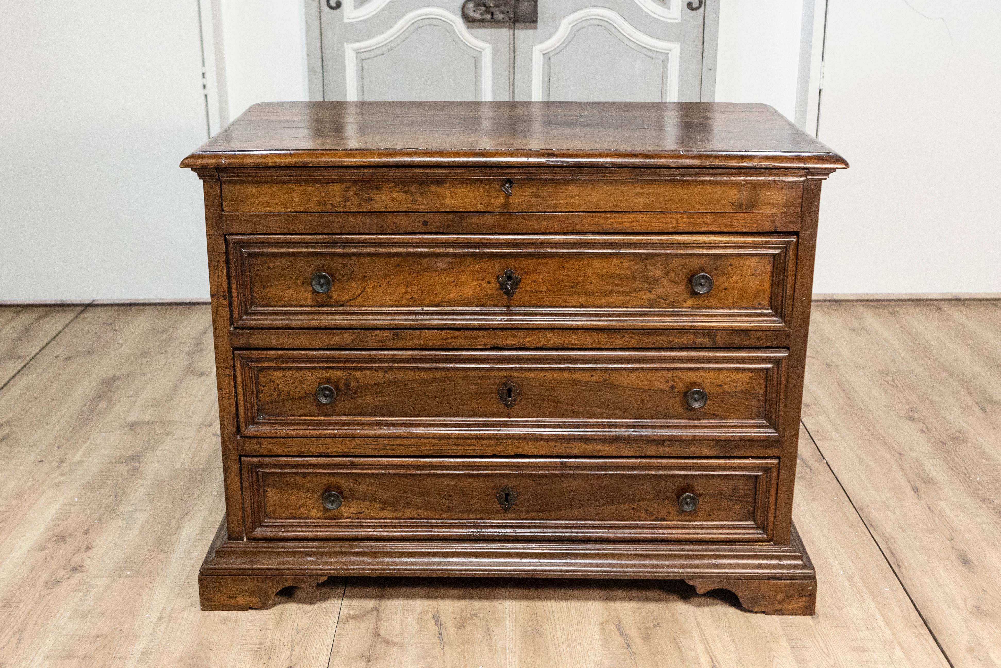 Una commode italiana in noce del XVII secolo con quattro cassetti e piedi a staffa intagliati. Questa squisita toilette in noce italiana del XVII secolo presenta un piano rettangolare con bordi smussati che aggiungono un tocco raffinato alla sua