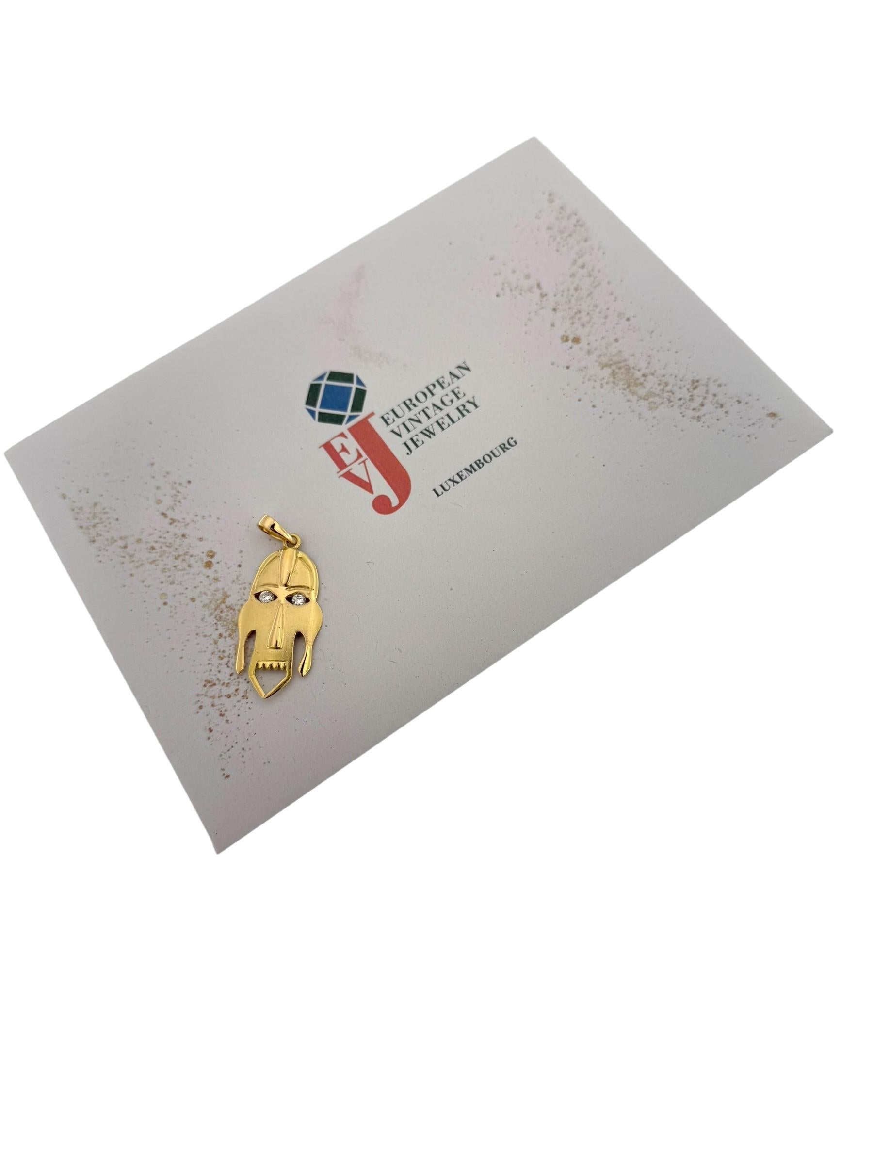 Questo ciondolo tribale italiano in oro giallo 18kt è un pezzo sorprendente e artistico, ispirato ad antichi motivi tribali e magistralmente realizzato in oro massiccio. Il ciondolo presenta il disegno di un volto tribale stilizzato che trasmette un