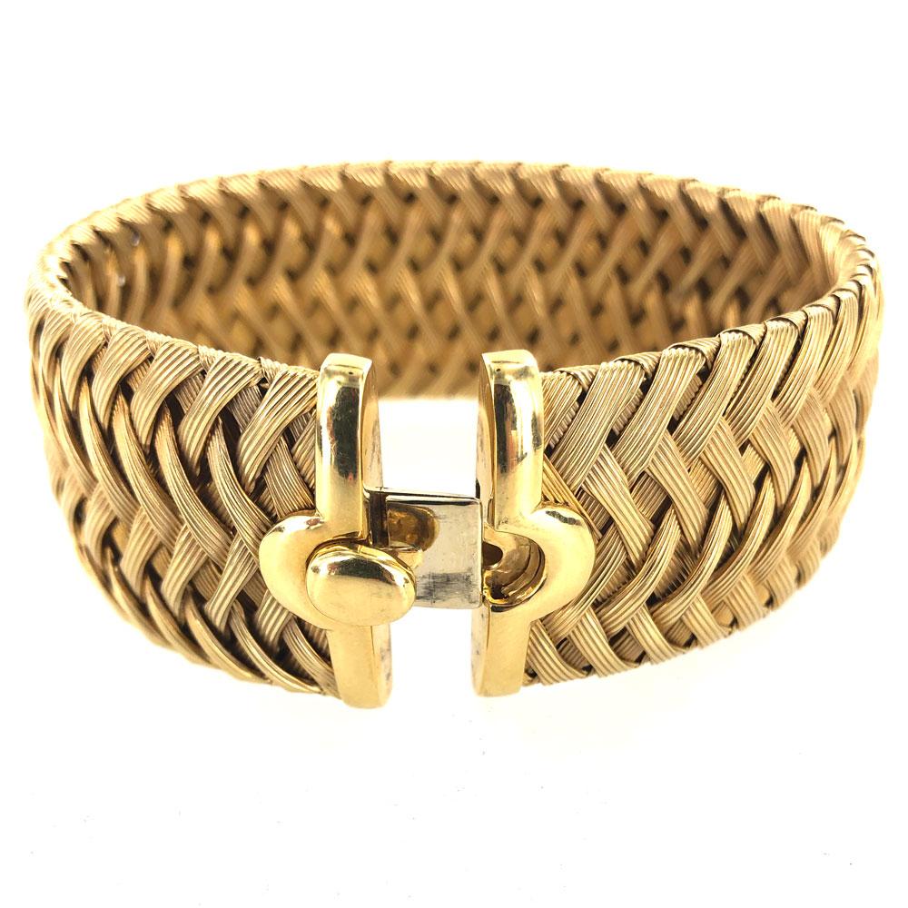 Beautifully crafted Italian woven bracelet fashioned in 18 karat yellow gold. The wide soft bangle measures 1.1 inches in width, 2.5 inches in diameter, and approximately 7 inches in circumference. 