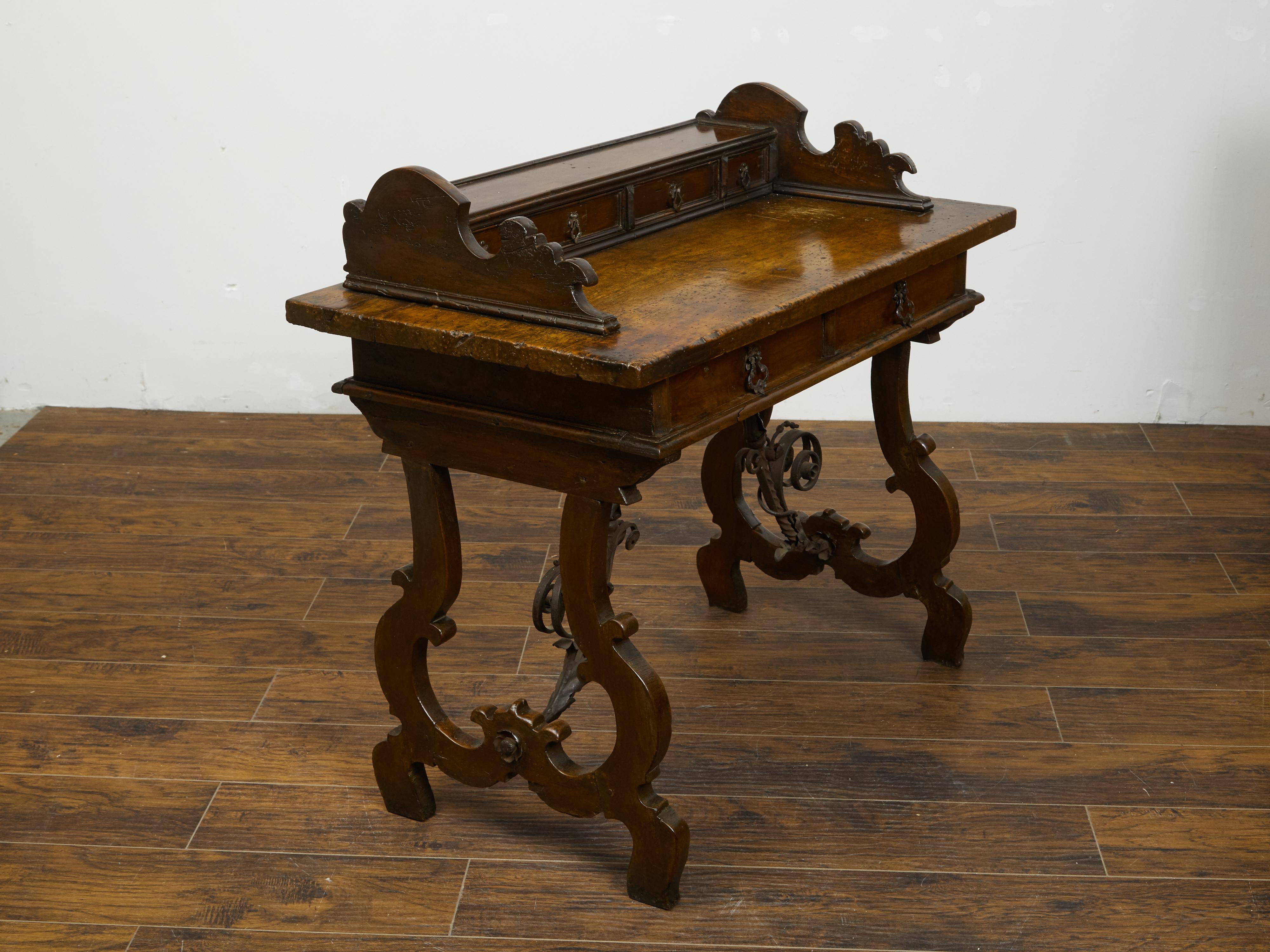 Ein italienischer Barocktisch aus Nussbaumholz aus dem frühen 19. Jahrhundert mit Schubladen, leierförmigem Sockel und schmiedeeiserner Bahre. Dieser Tisch aus Nussbaumholz, der in den frühen Jahren des 19. Jahrhunderts in Italien hergestellt wurde,