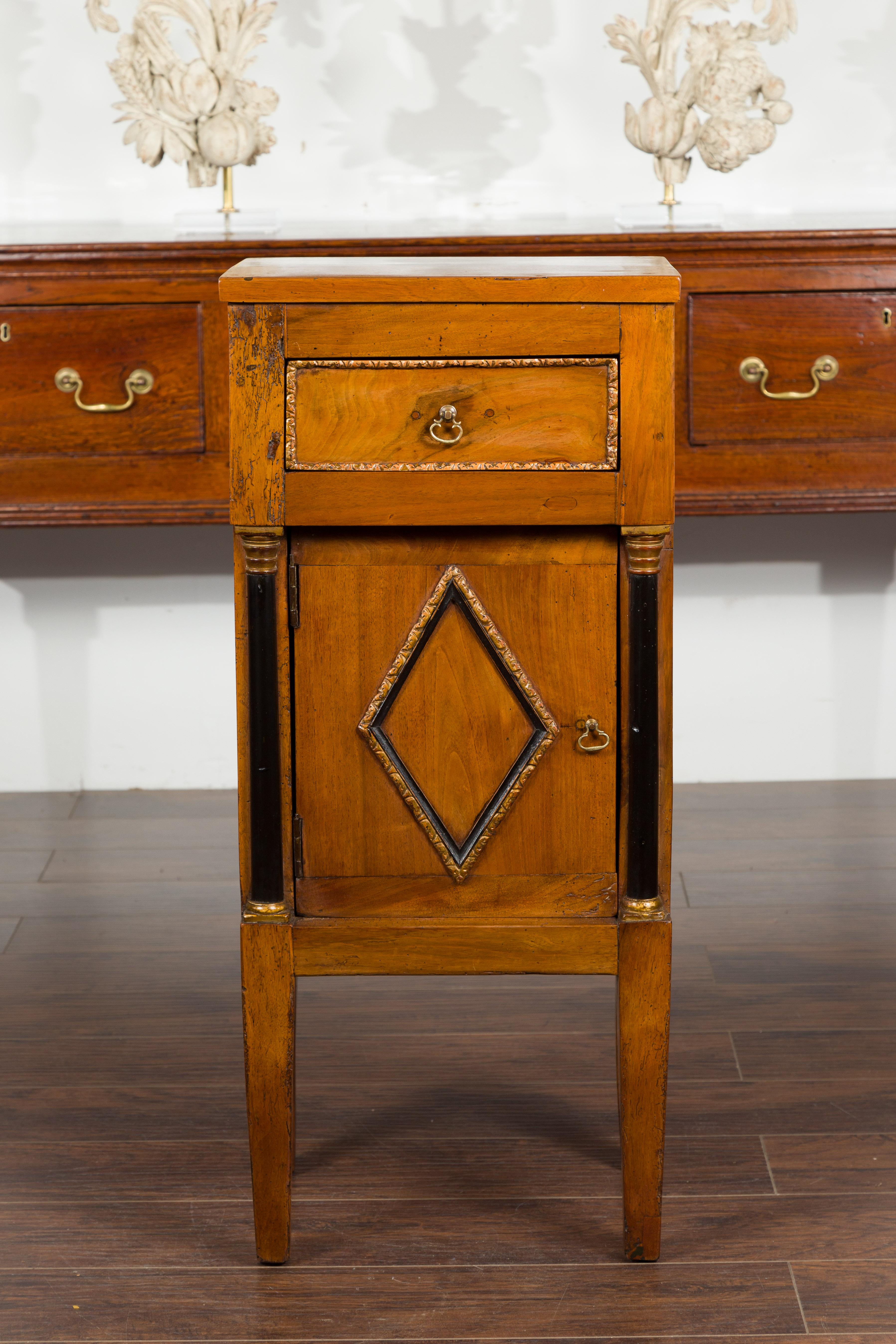 An Italian Empire period walnut cabinet from the early 19th century, with black and gold accents and diamond motifs. Created in Italy during the early years of the 19th century, this Empire cabinet features a rectangular top sitting above a single