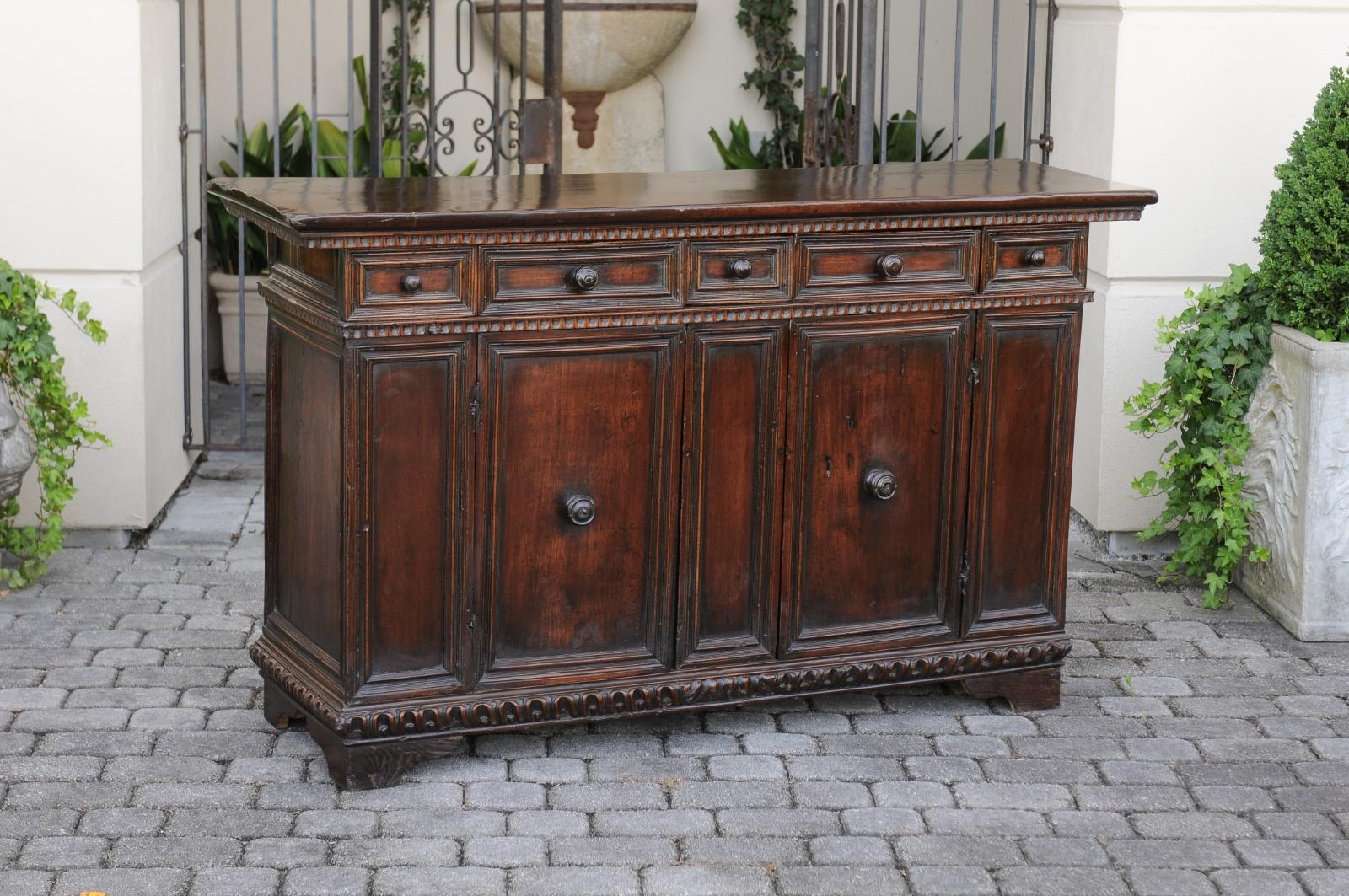 An Italian walnut credenza from the early 19th century, with five drawers, two doors and carved accents. Born in Italy during the early years of the 19th century, this exquisite walnut credenza features a rectangular top adorned with scooped