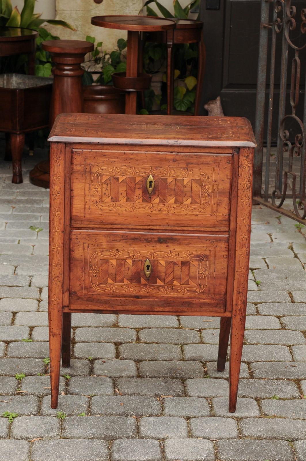 A petite Italian neoclassical walnut commode from the early 19th century, with geometrical and floral inlaid motifs. Born in Italy during the early years of the 19th century, this small neoclassical commode features a rectangular top with beveled