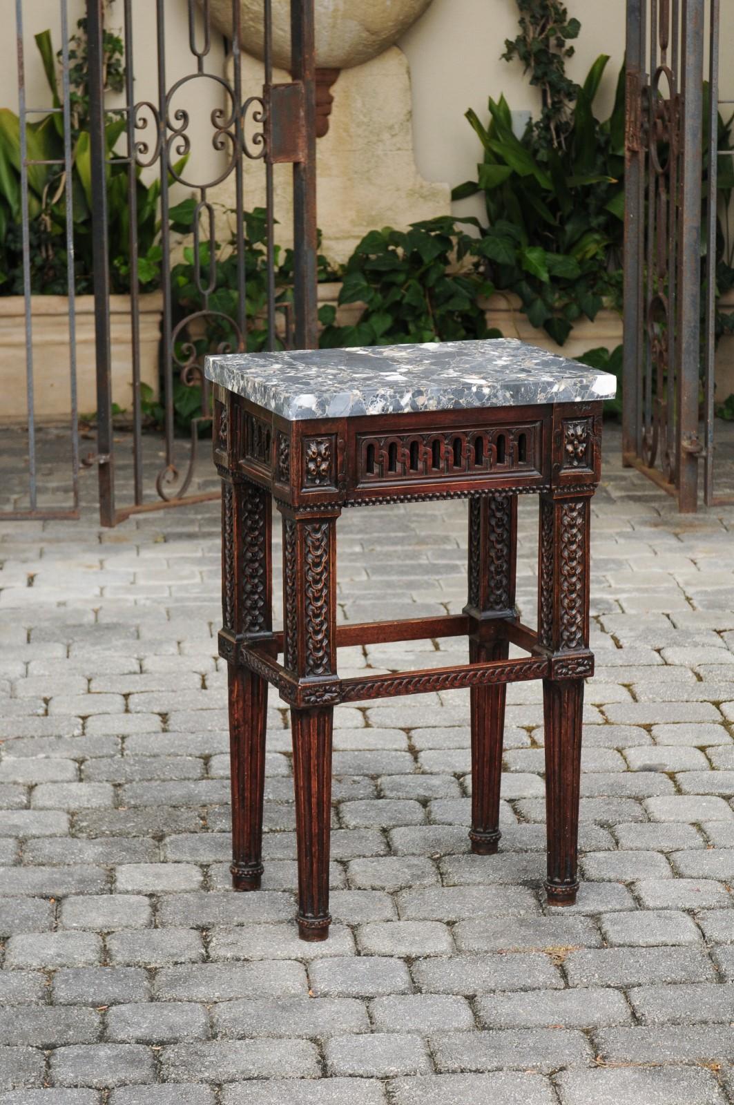 An Italian neoclassical period walnut side table from the early 19th century, with richly carved décor and grey marble top. Born in Italy during the early years of the 19th century, this exquisite side table features a rectangular variegated grey