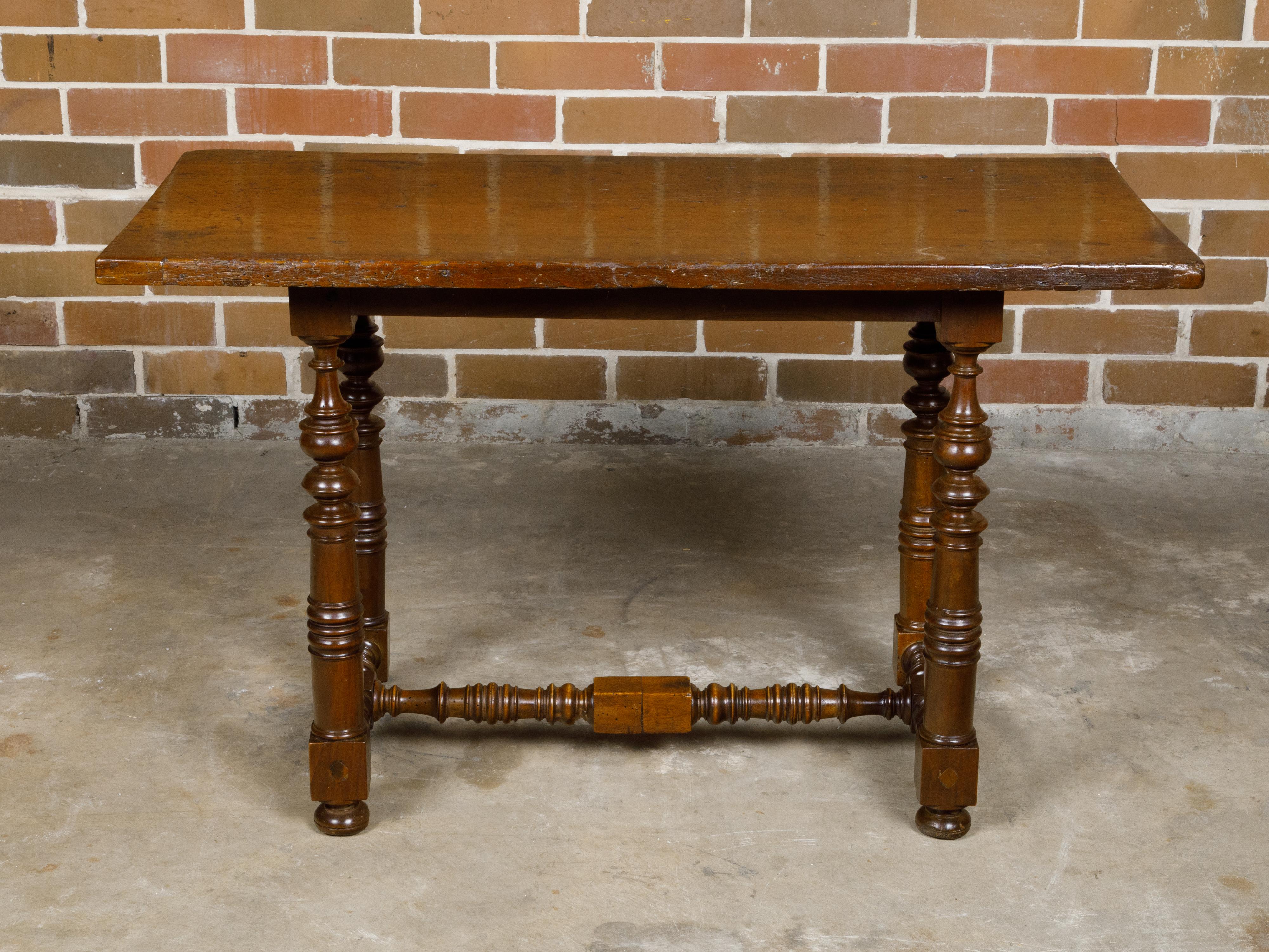An Italian Baroque style walnut side table from circa 1800 with spool legs, H-Form cross stretcher and bun feet. This Italian Baroque-style walnut side table, dating back to circa 1800, is a testament to timeless elegance and refined craftsmanship.