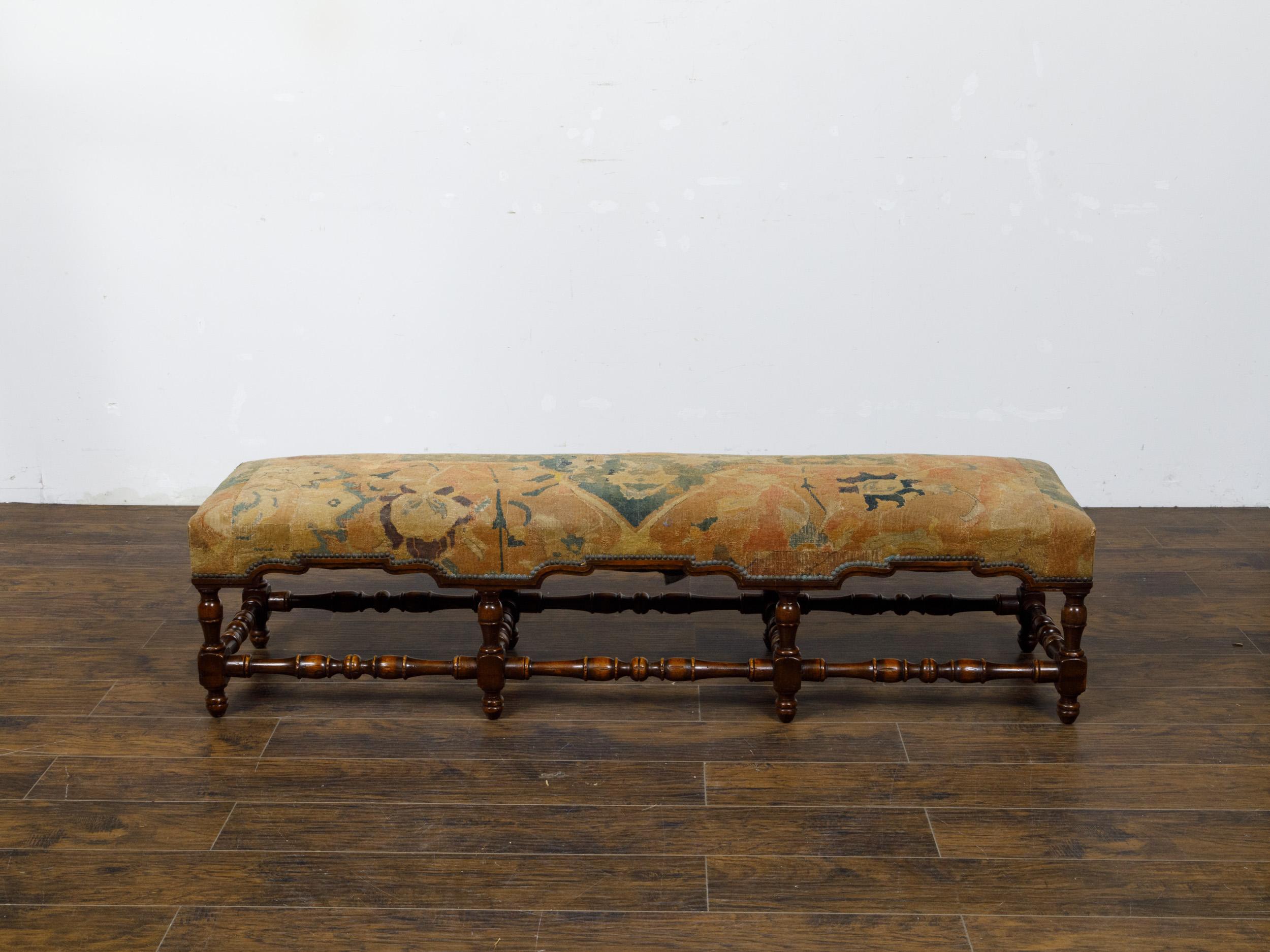 An Italian walnut bench from circa 1800 with turned base and old tapestry upholstered seat. This elegant Italian walnut bench from circa 1800 exudes timeless charm and historical significance. The bench features an exquisitely turned base that