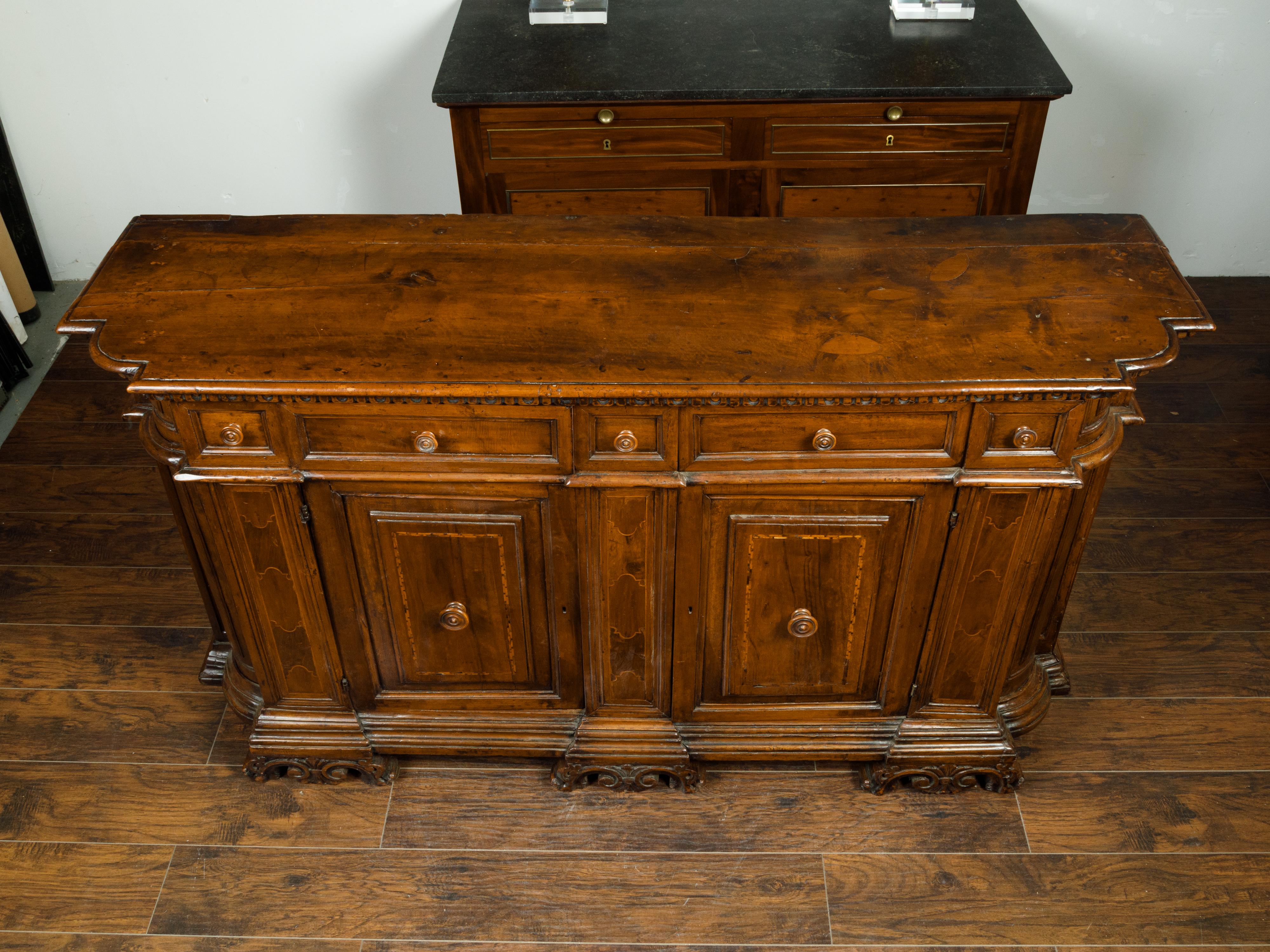 An Italian walnut credenza from the early 19th century, with drawers over doors, inlay and carved feet. Created in Italy in the early years of the 19th century, this walnut credenza features a rectangular top with rounded corners in the front,