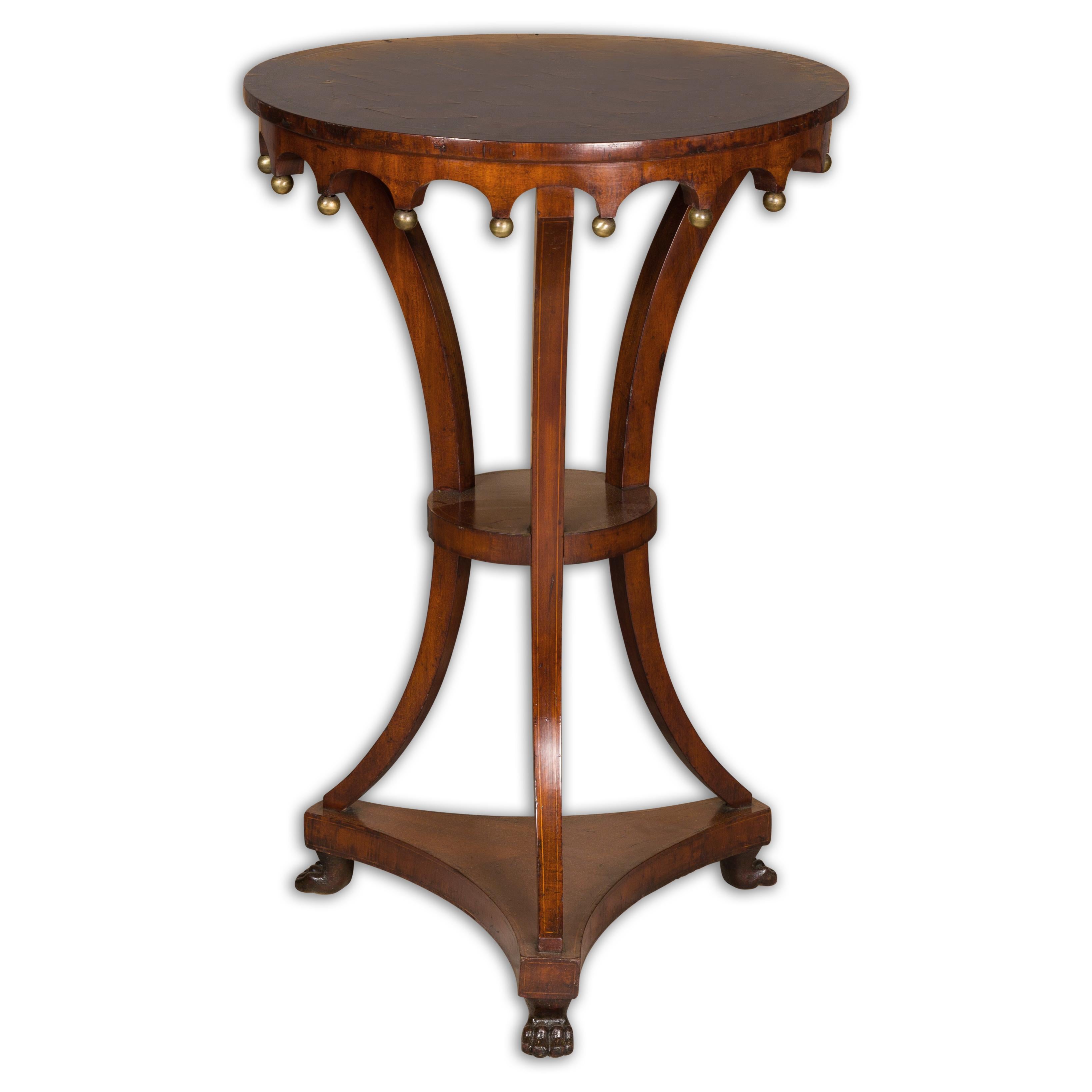 An Italian walnut guéridon side table from the early 19th century with parquetry top, carved apron, petite gilt spheres and lion paw feet. Presenting a piece of Italian design, this early 19th-century walnut guéridon side table is a lovely