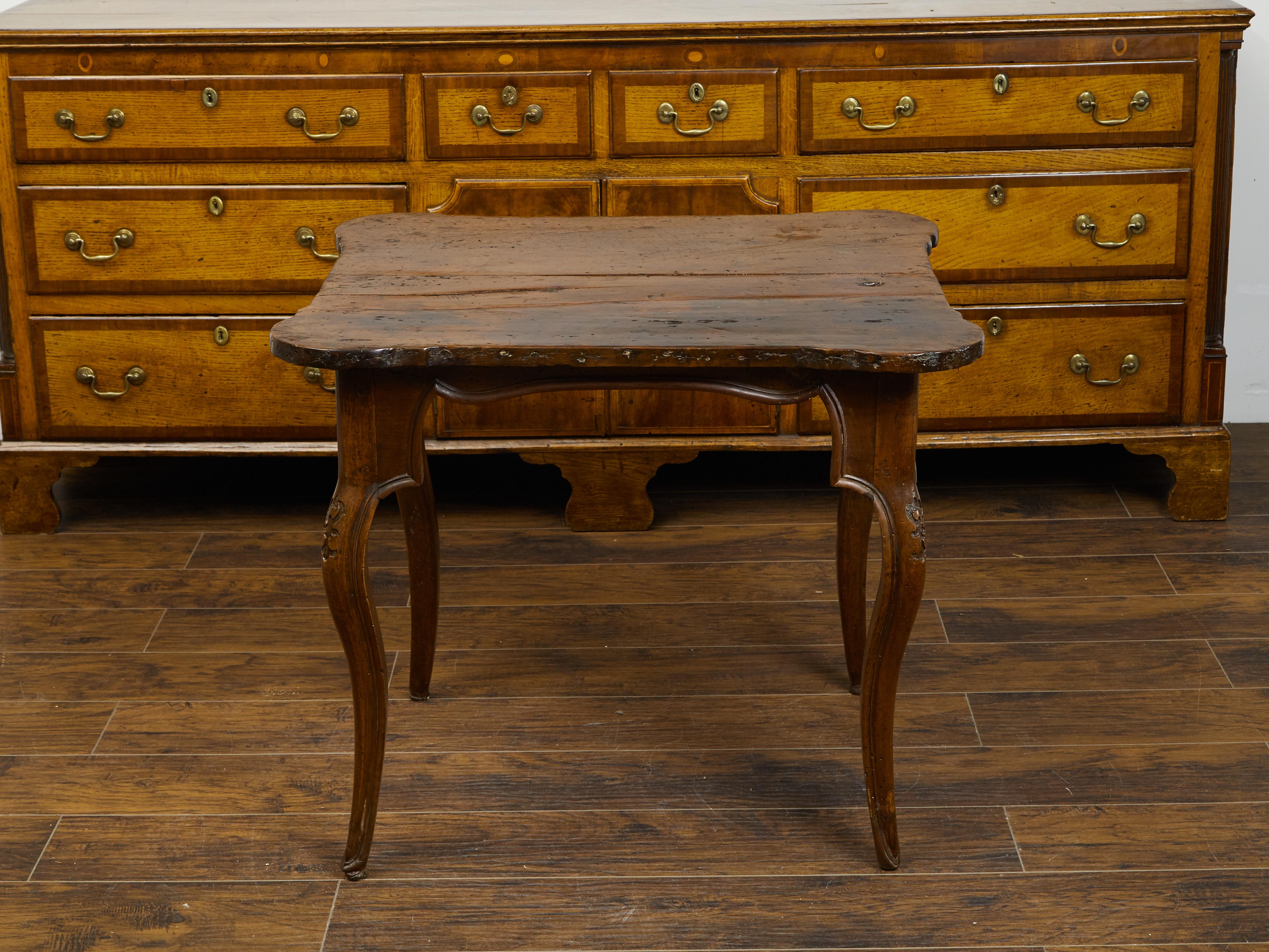 An Italian walnut side table from the early 19th century, with carved apron and cabriole legs. Created in Italy during the first decade of the 19th century, this walnut side table features a rectangular top with rounded corners, sitting above an