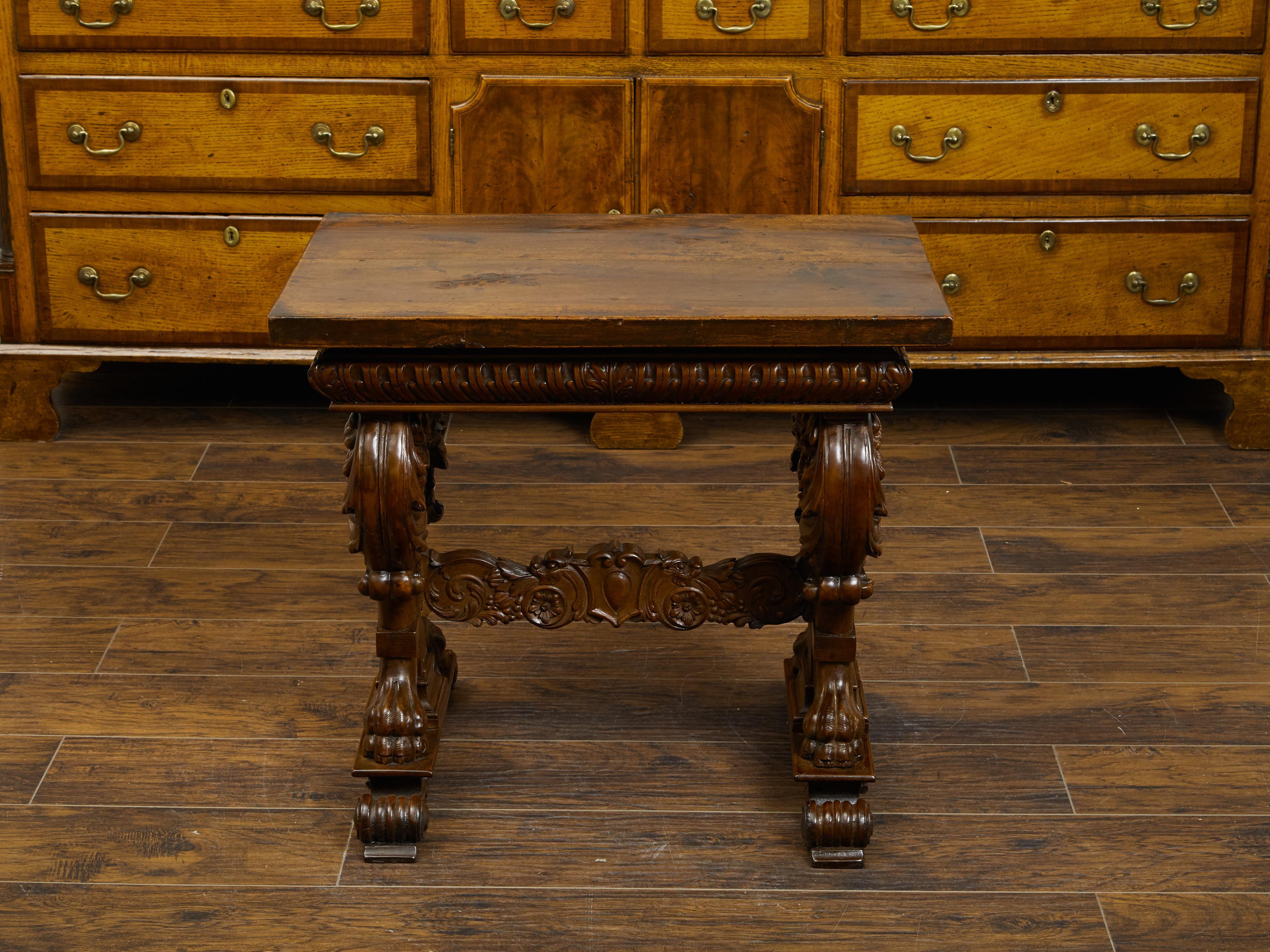 An Italian walnut small side table from the early 19th century, with lions' heads and richly carved trestle base. Created in Italy during the early years of the 19th century, this walnut side table features a rectangular top sitting above an apron