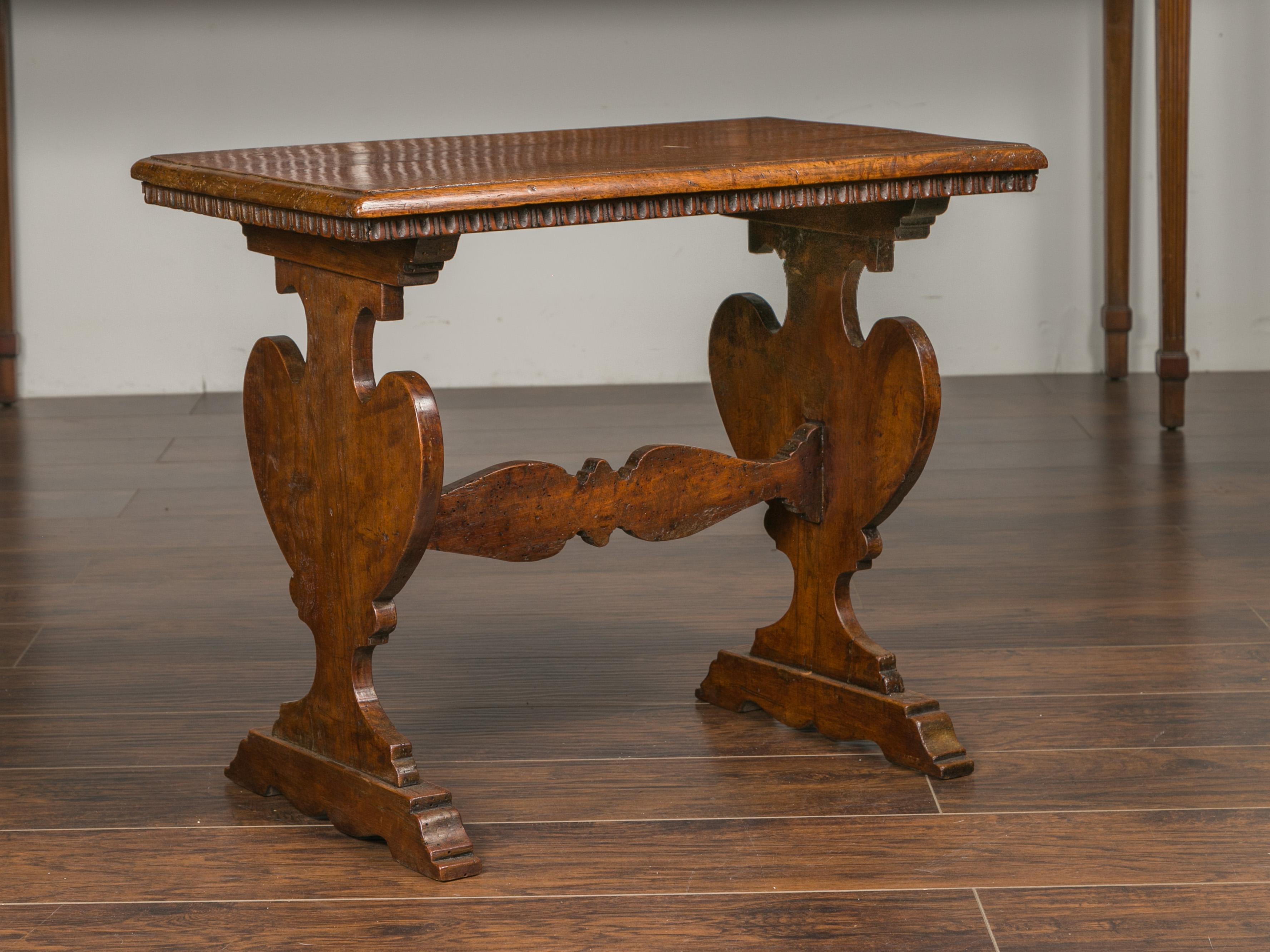 An Italian walnut low side table from the early 19th century, with trestle base and carved scoop patterns. Created in Italy during the early years of the 19th century, this walnut side table features a rectangular top with beveled edges, sitting