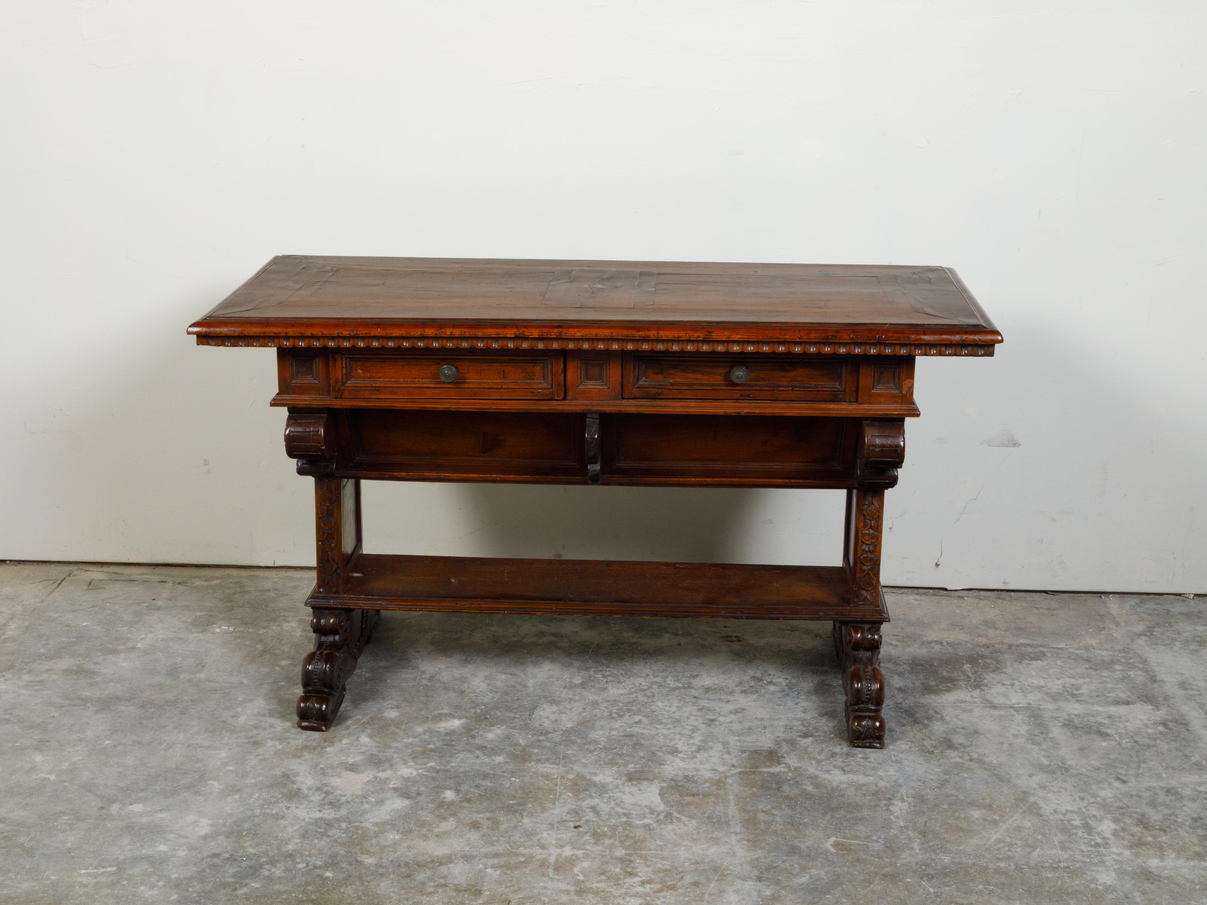 An Italian walnut table from the early 19th century, with carved motifs and two drawers. Created in Italy during the early years of the 19th century, this walnut table features a rectangular top sitting above a scoop molding. Showcasing two drawers,