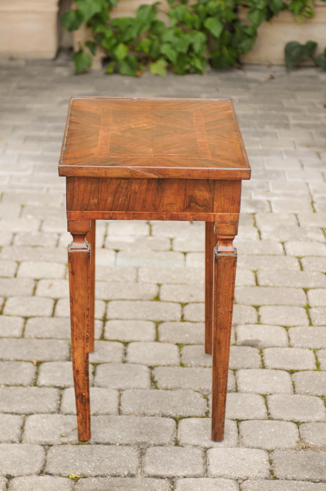 A petite Italian neoclassical walnut veneered side table from the first quarter of the 19th century, with single drawer and tapered legs. This Italian side table features an exquisite rectangular top, exquisitely adorned with walnut veneer