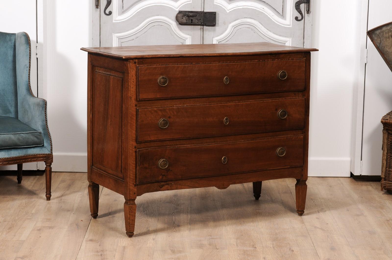 An Italian walnut commode from circa 1820 with serpentine front and carved tapered feet. Introduce a dash of Italian allure into your home with this walnut commode, hailing from the rich artistic landscapes of the 1820s. Marrying practicality and