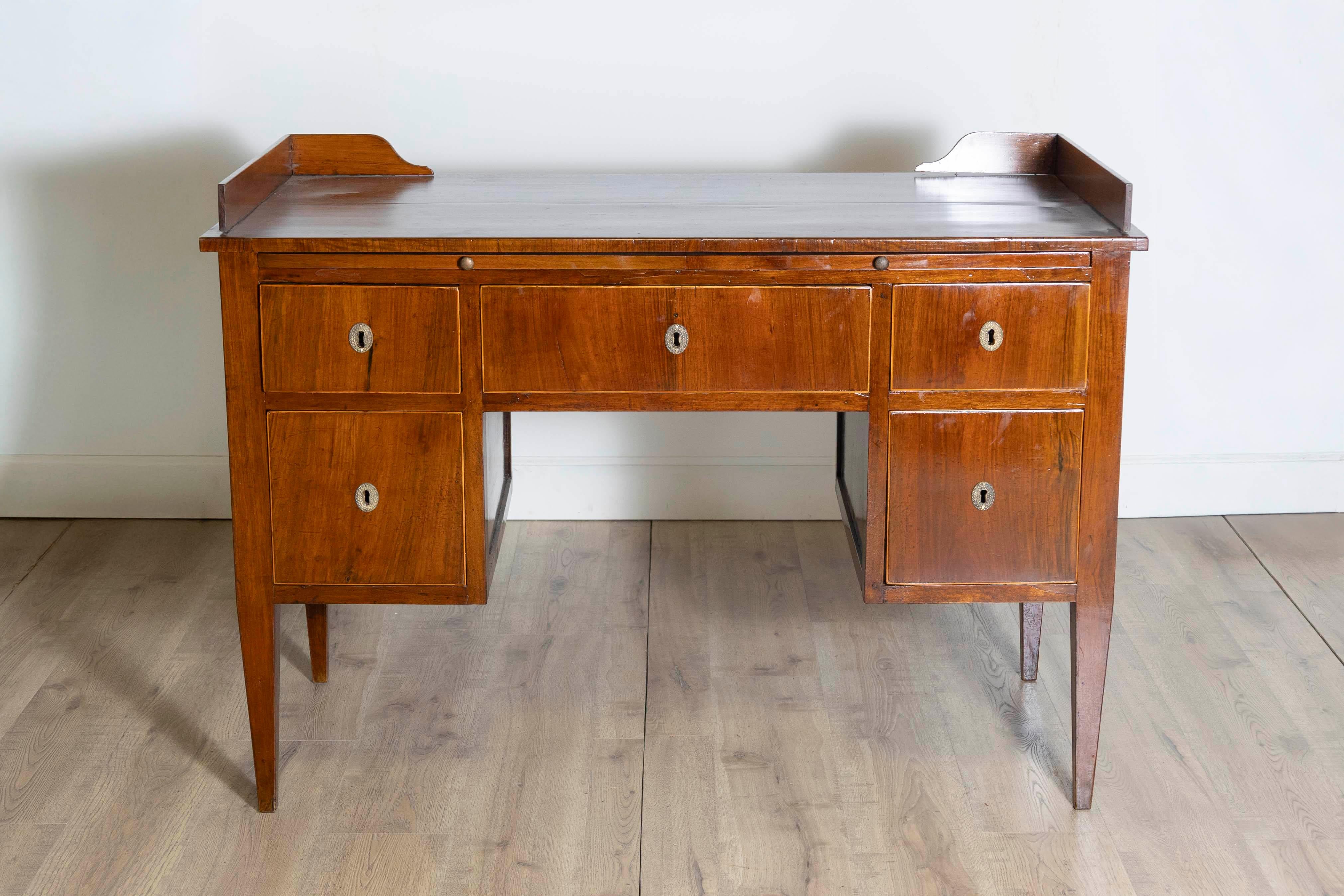 An Italian walnut and mahogany desk from circa 1820 with dark brown leather pull-out drawer, five drawers and thin banding around the drawers. This Italian walnut and mahogany desk from circa 1820 is a fine example of early 19th-century