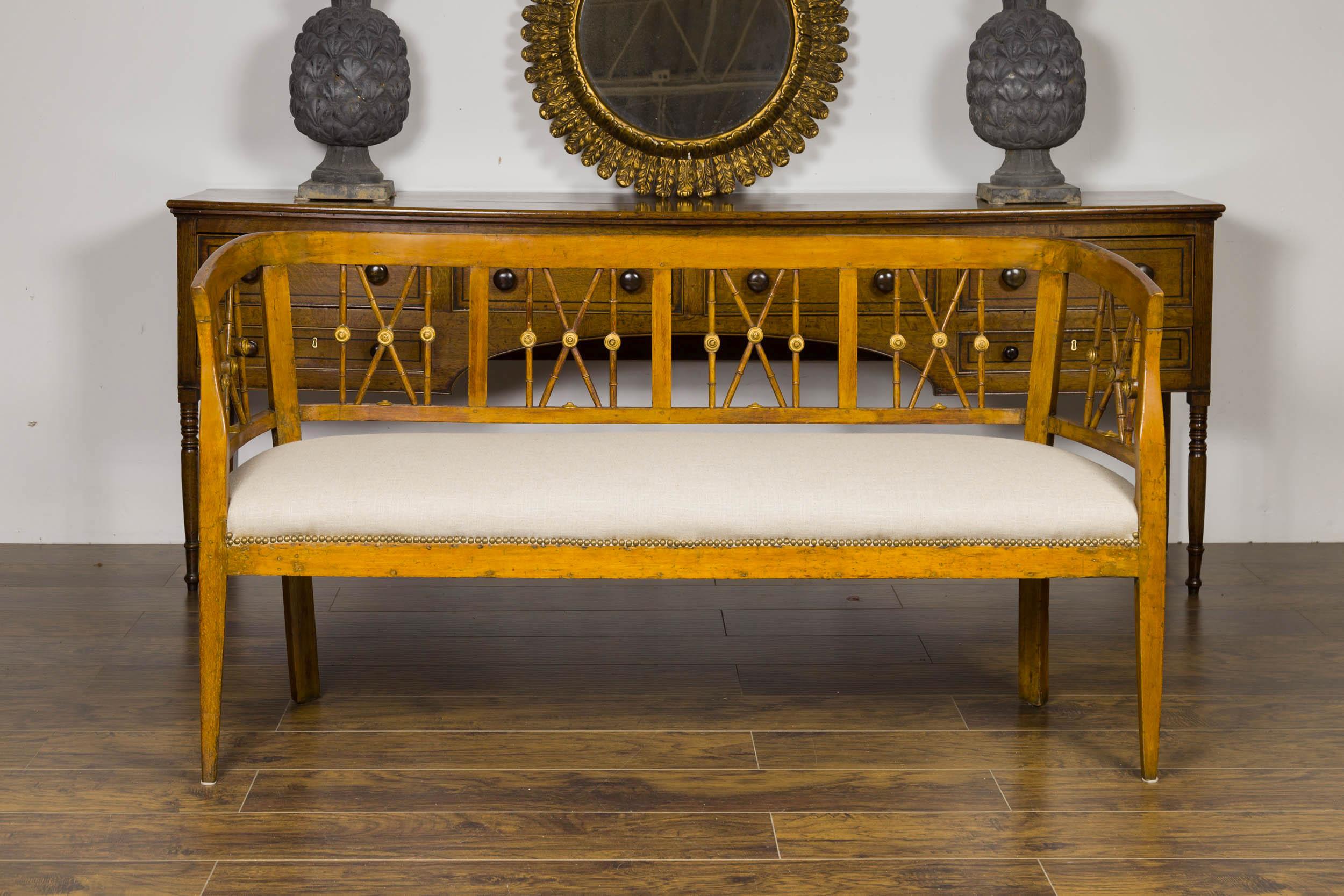 An Italian walnut settee from the early 19th century, with X motifs, gilded medallions and new upholstery. Born in Italy during the first quarter of the 19th century, this walnut settee features a pierced back, accented with X motifs and gilded