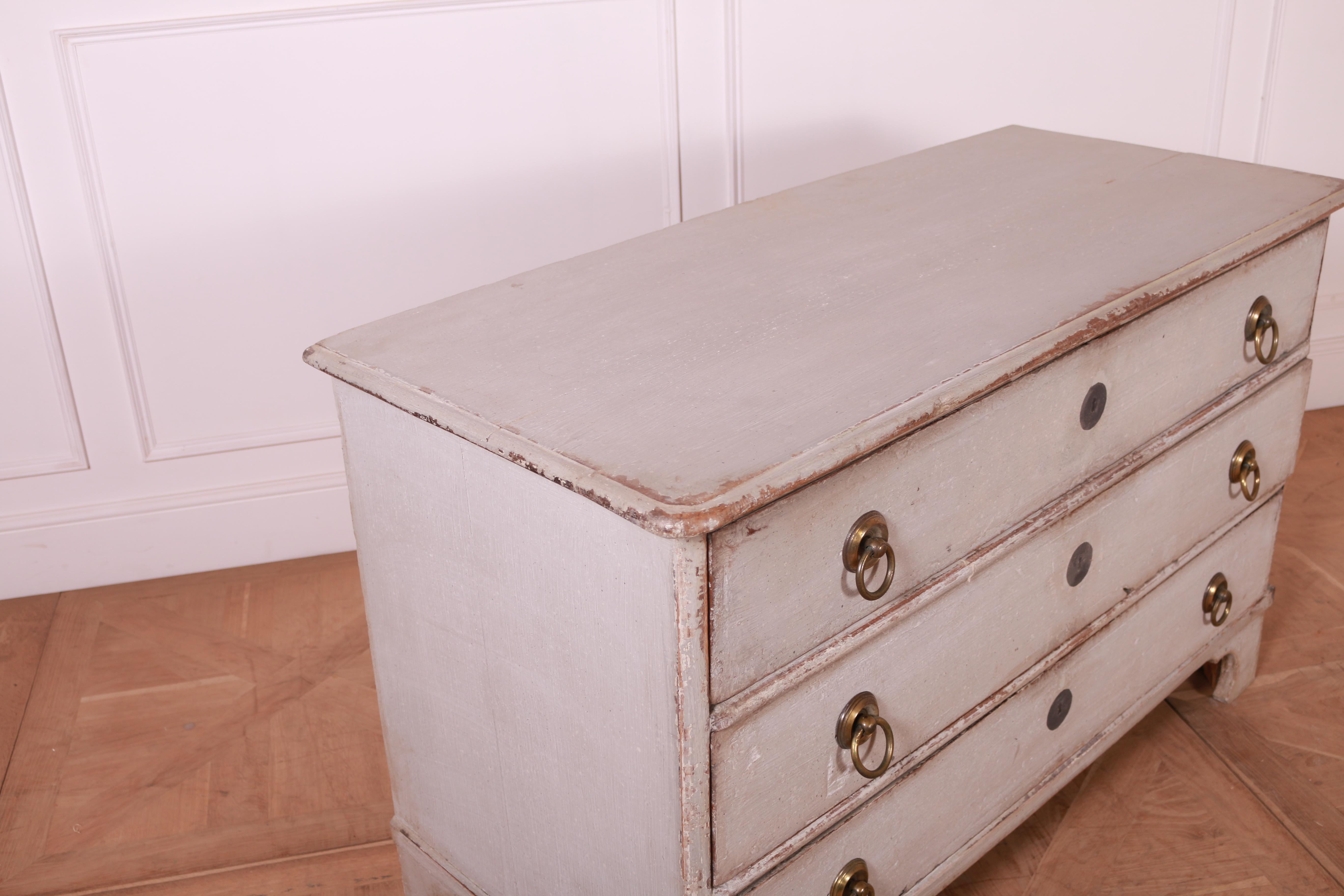 An Italian three-drawer commode from circa 1840 with light gray painted finish and carved bracket feet. Experience the blend of rustic charm and elegant design with this Italian three-drawer commode from circa 1840, exquisitely finished in a light