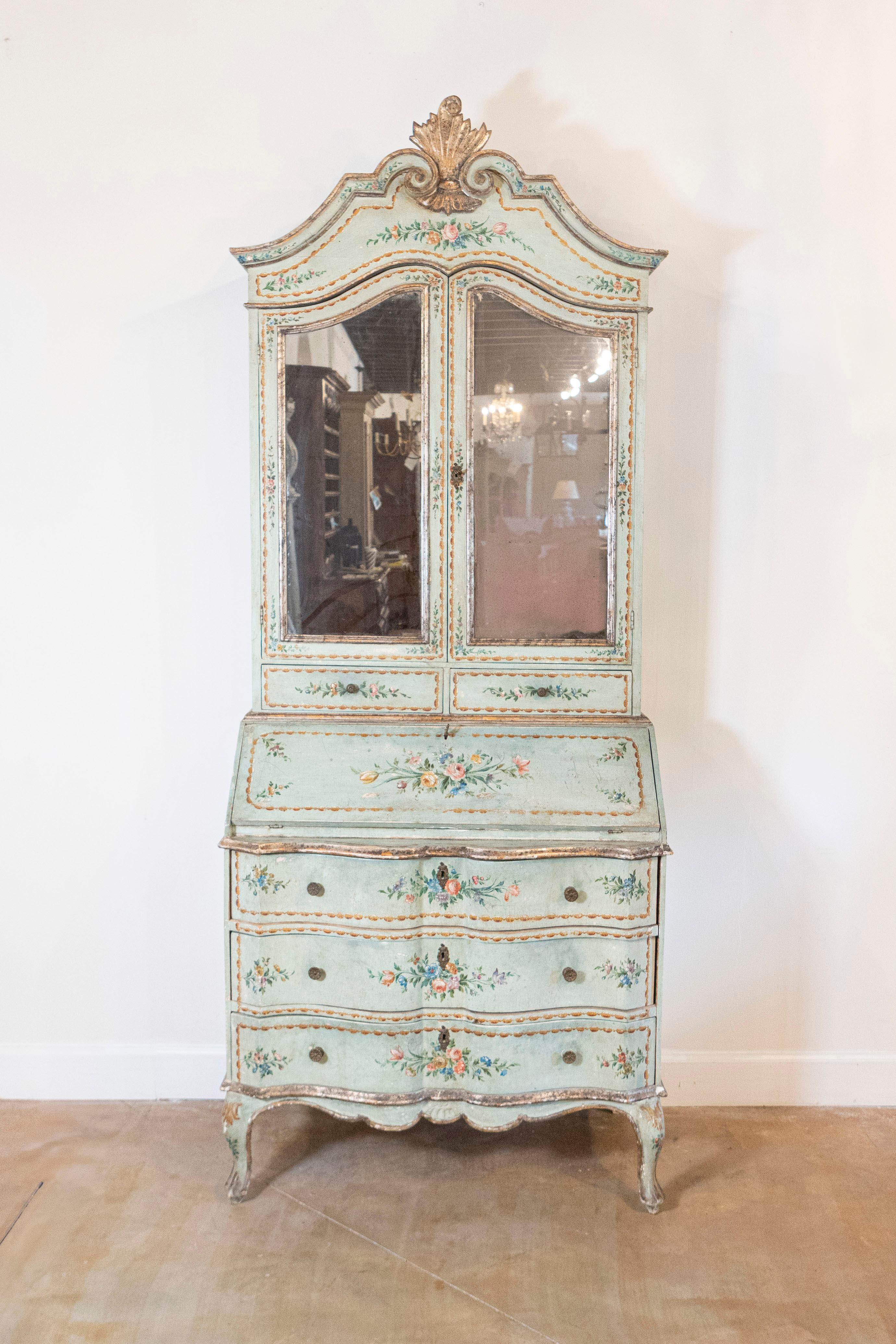 An Italian Rococo style two-part secretary from the mid-19th century, with slanted desk, mirrored doors and original paint. How not to fall head over heels in love with this Rococo style Italian tall secretary? Topped with a voluted cornice accented