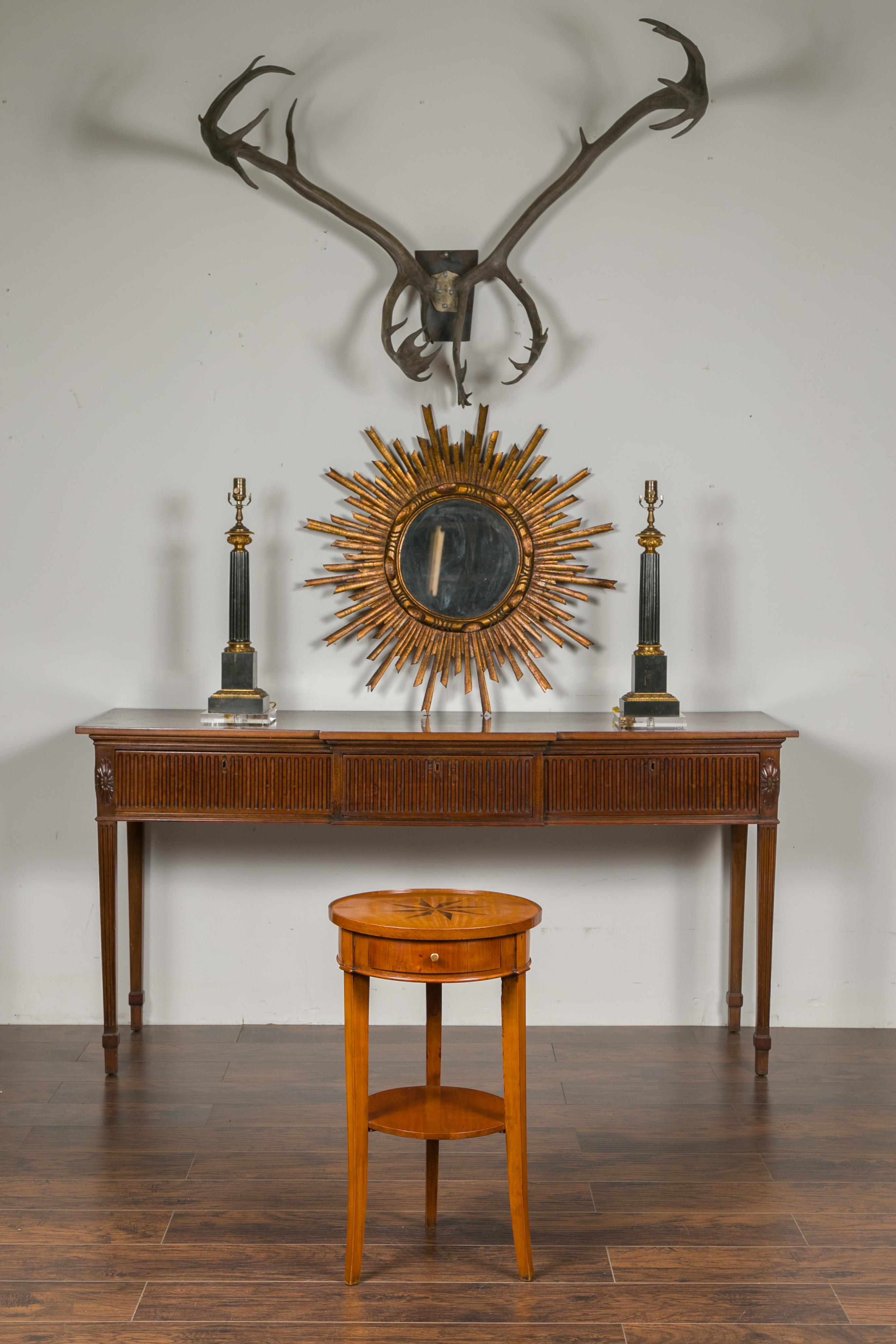 An Italian walnut guéridon table from the mid-19th century, with star marquetry, single drawer and lower shelf. Created in Italy during the 1850s, this side table features a circular top with slightly raised edges, adorned in its center with a