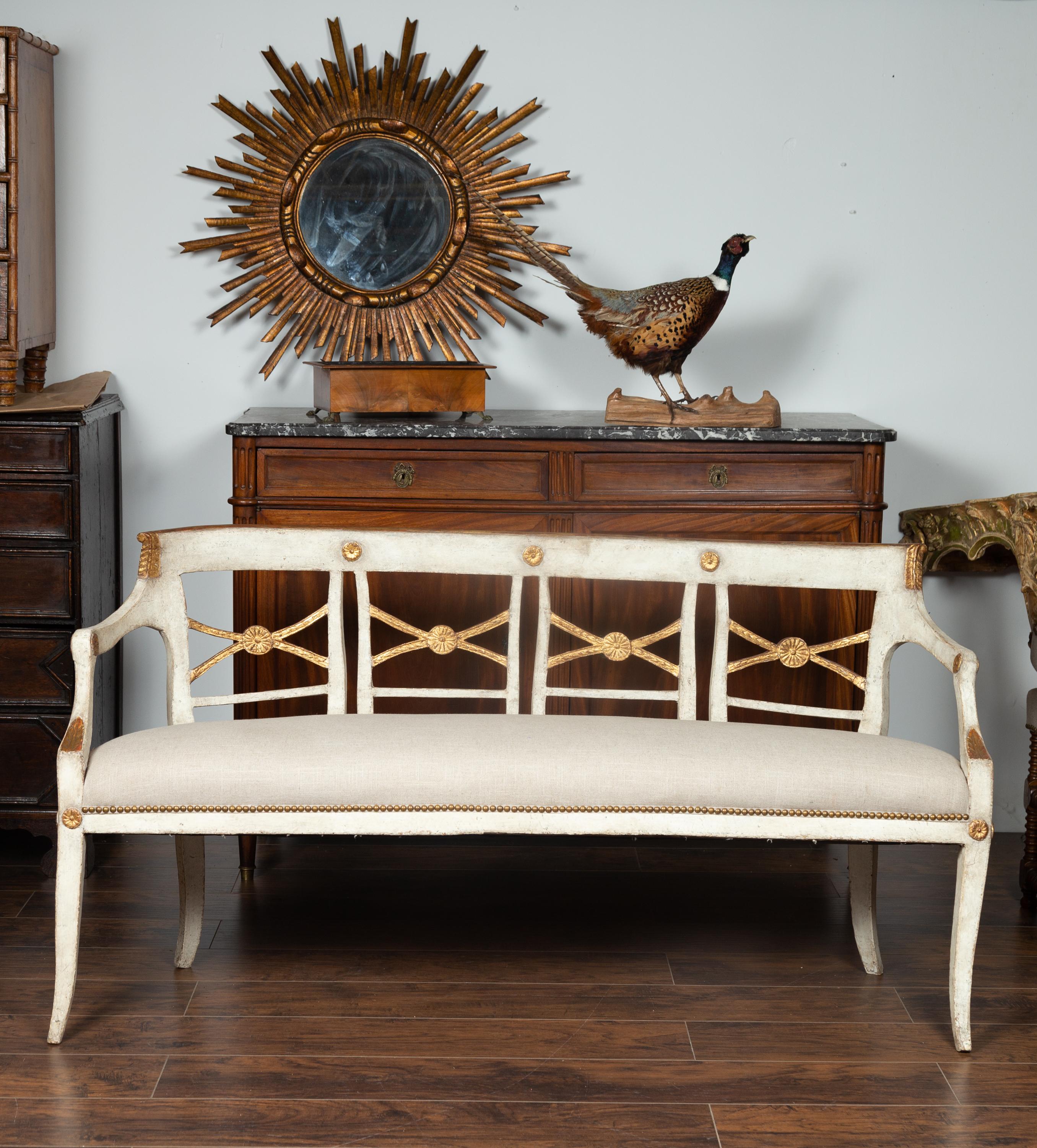 An Italian painted wood bench from the mid 19th century, with gilded accents and new upholstery. Born in Italy during the third quarter of the 19th century, this exquisite bench features an open back, accented with gilded X-motifs and delicate