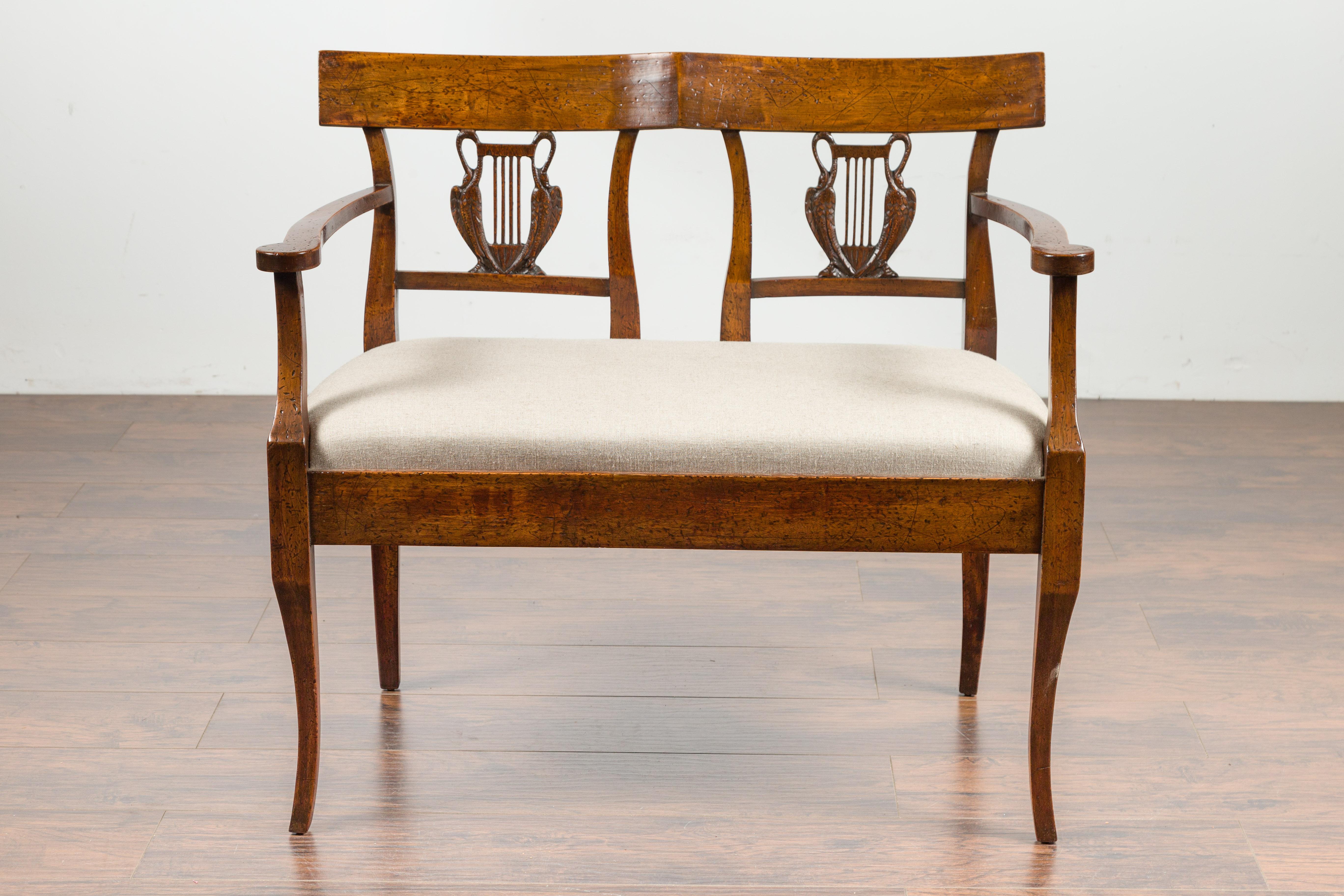 An Italian carved walnut two-seats settee from the late 19th century, with swan motifs and new upholstery. Created in Italy during the third quarter of the 19th century, this walnut settee features a sinuous back pierced with elegant swan motifs.