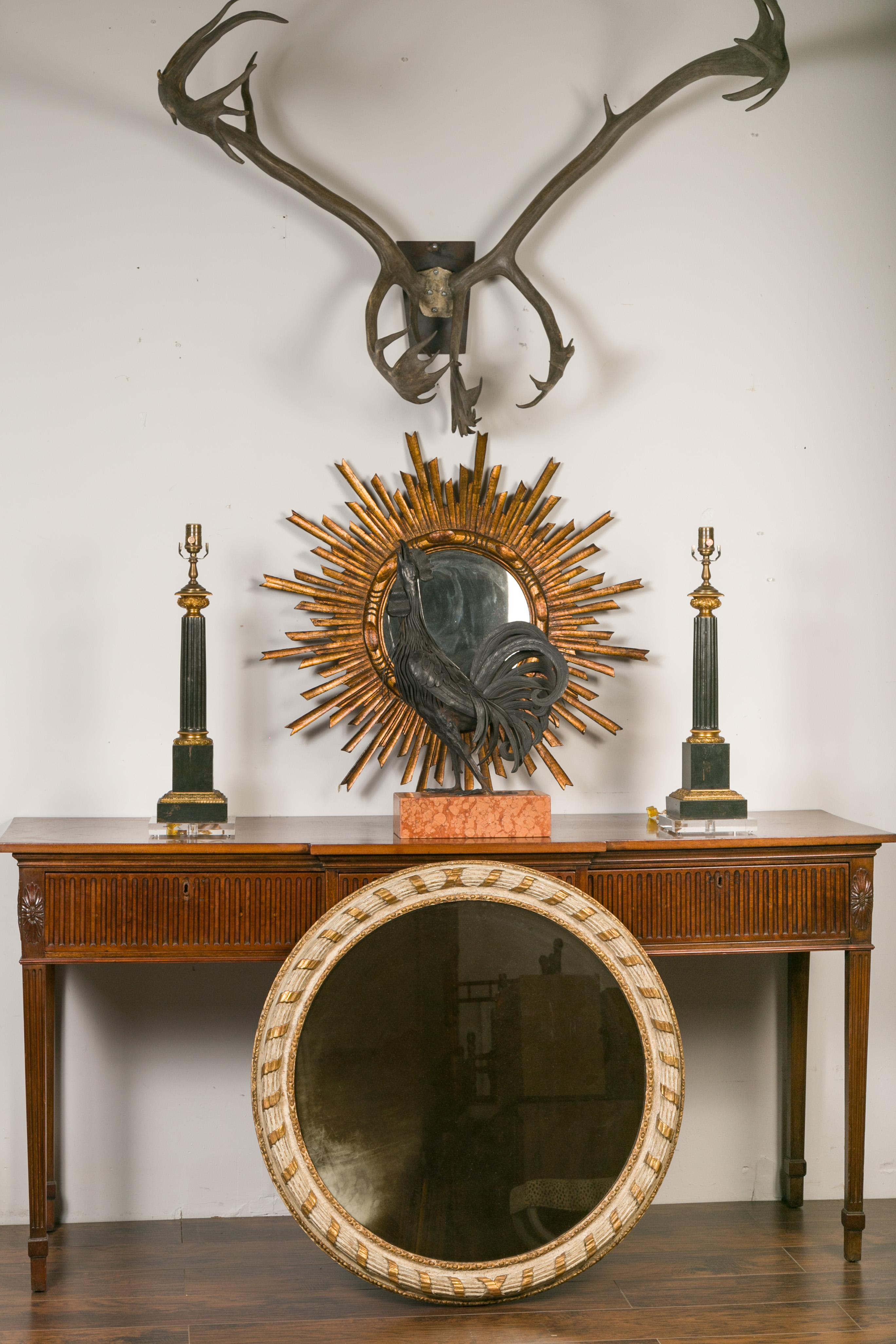 An Italian carved circular parcel-gilt and painted mirror from the late 19th century, with ribbon motif. Created in Italy during the last quarter of the 19th century, this mirror features a cream colored reeded frame highlighted with gilt motifs and